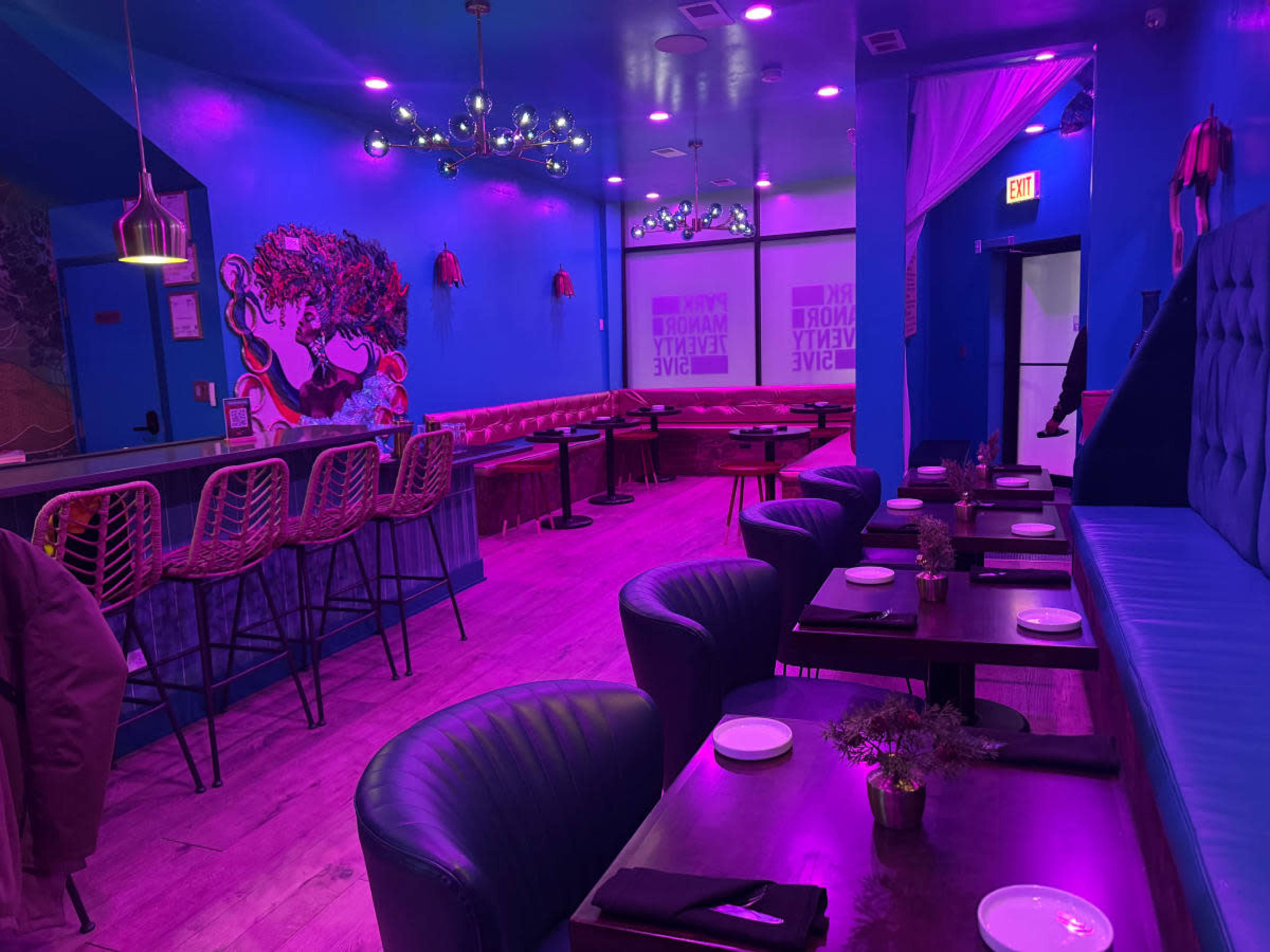The image shows a vibrant restaurant interior with purple walls, modern seating, and decorative lighting.
