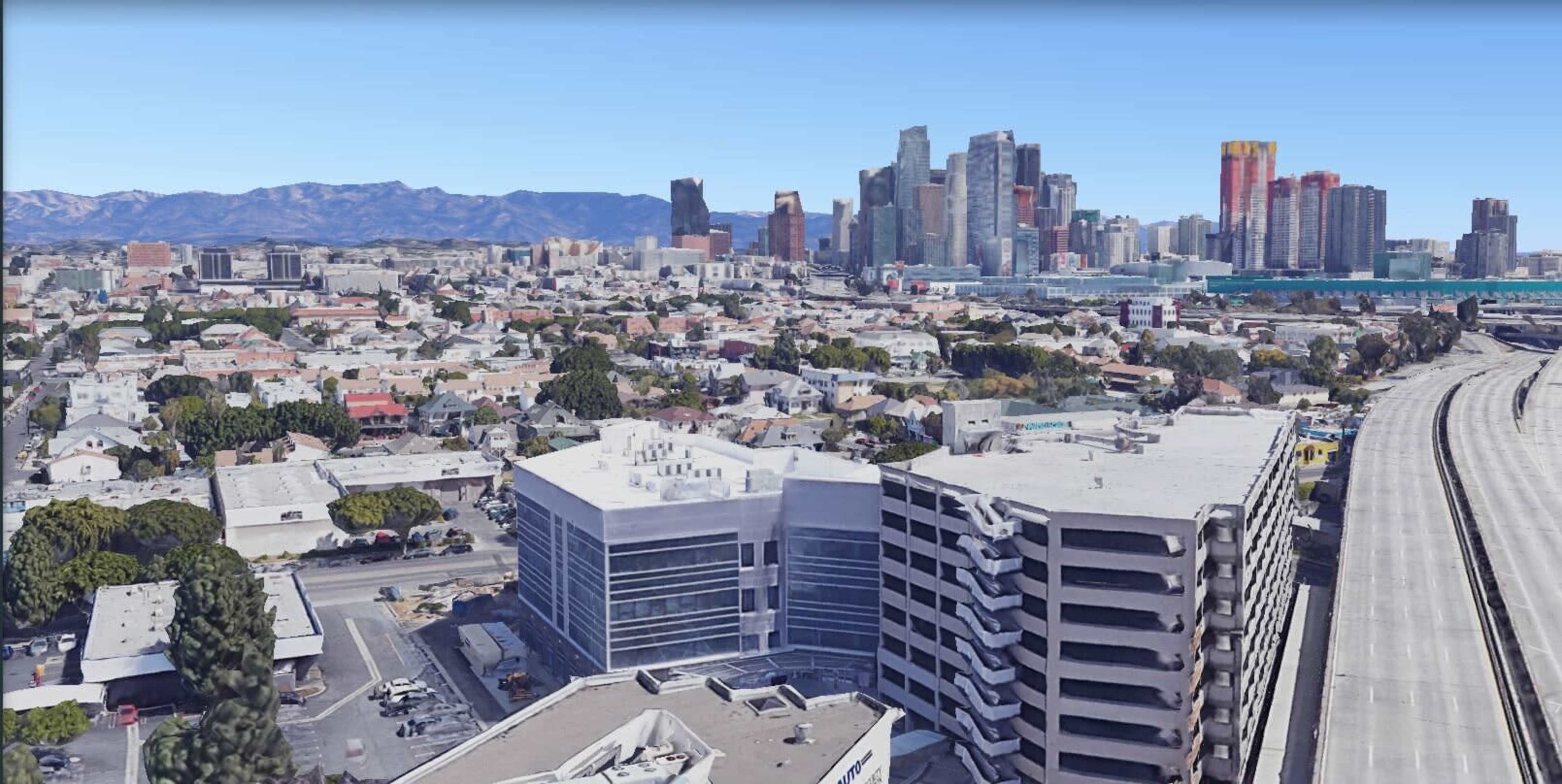 The image shows aerial view of a city skyline with a mix of residential buildings and skyscrapers in the background, alongside a highway.