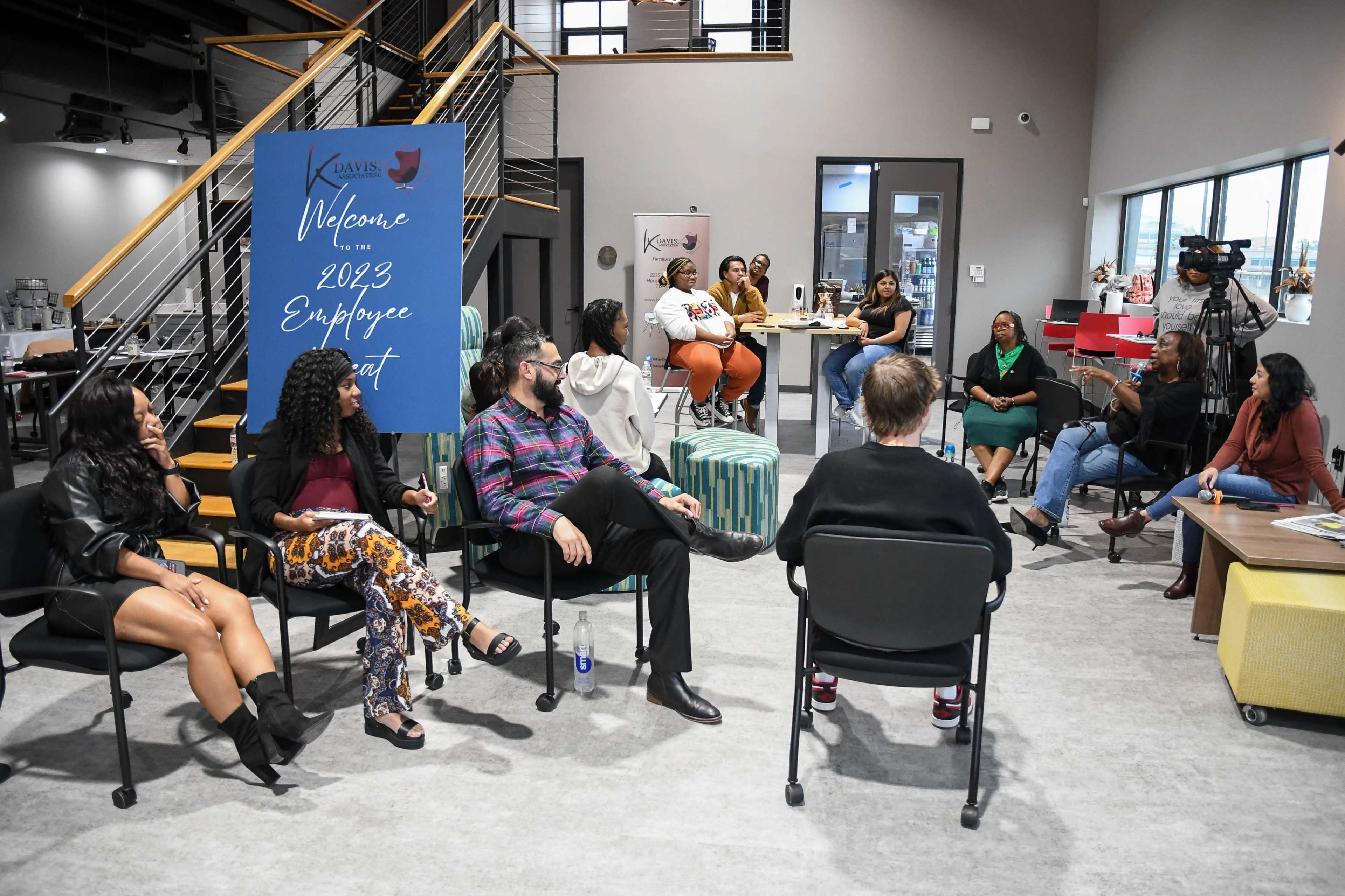 A group of employees is engaged in a discussion during a company meeting in a modern office space.