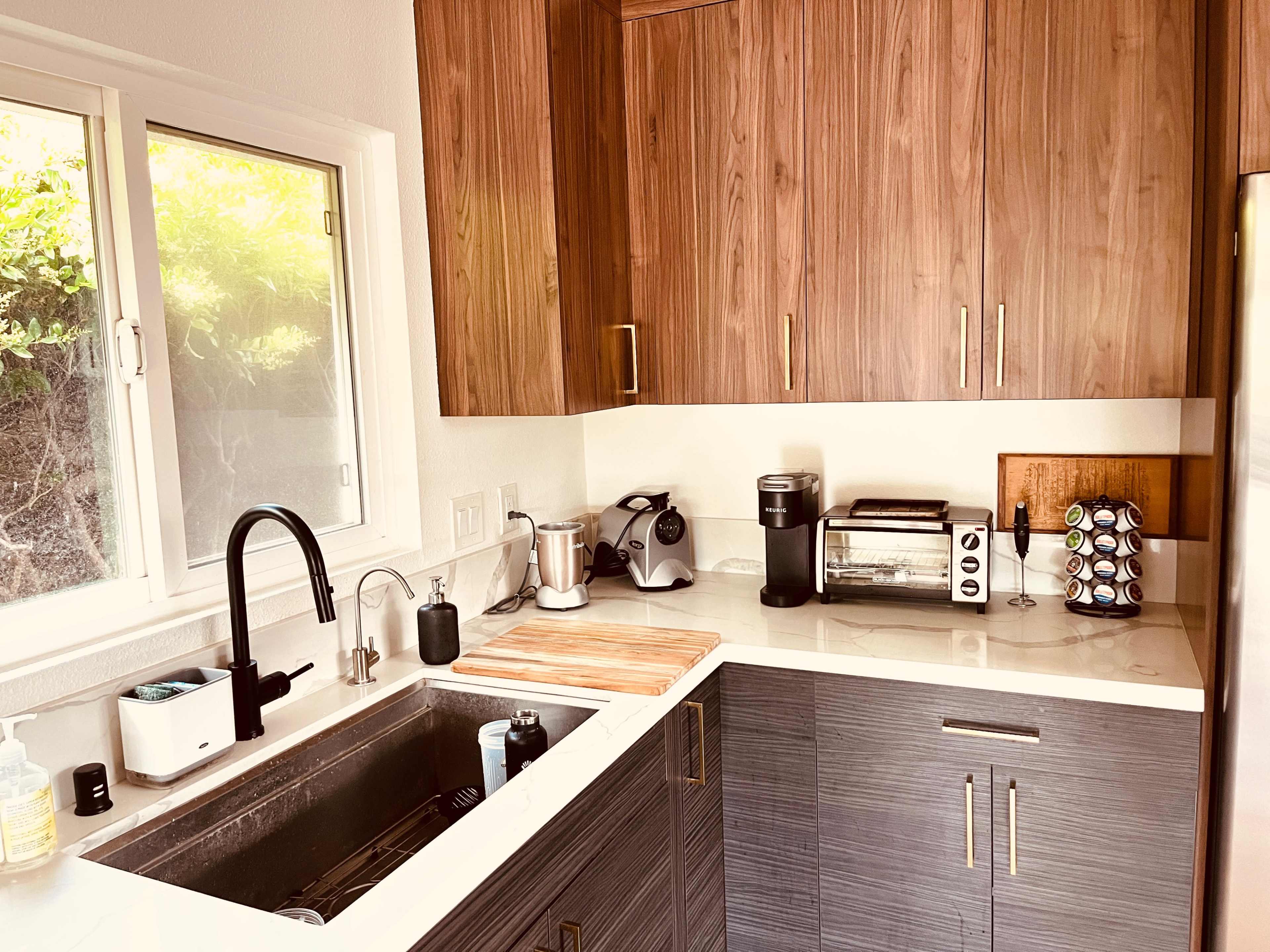 A modern kitchen with wooden cabinets, a stainless steel sink, and various appliances including a coffee maker and a toaster.