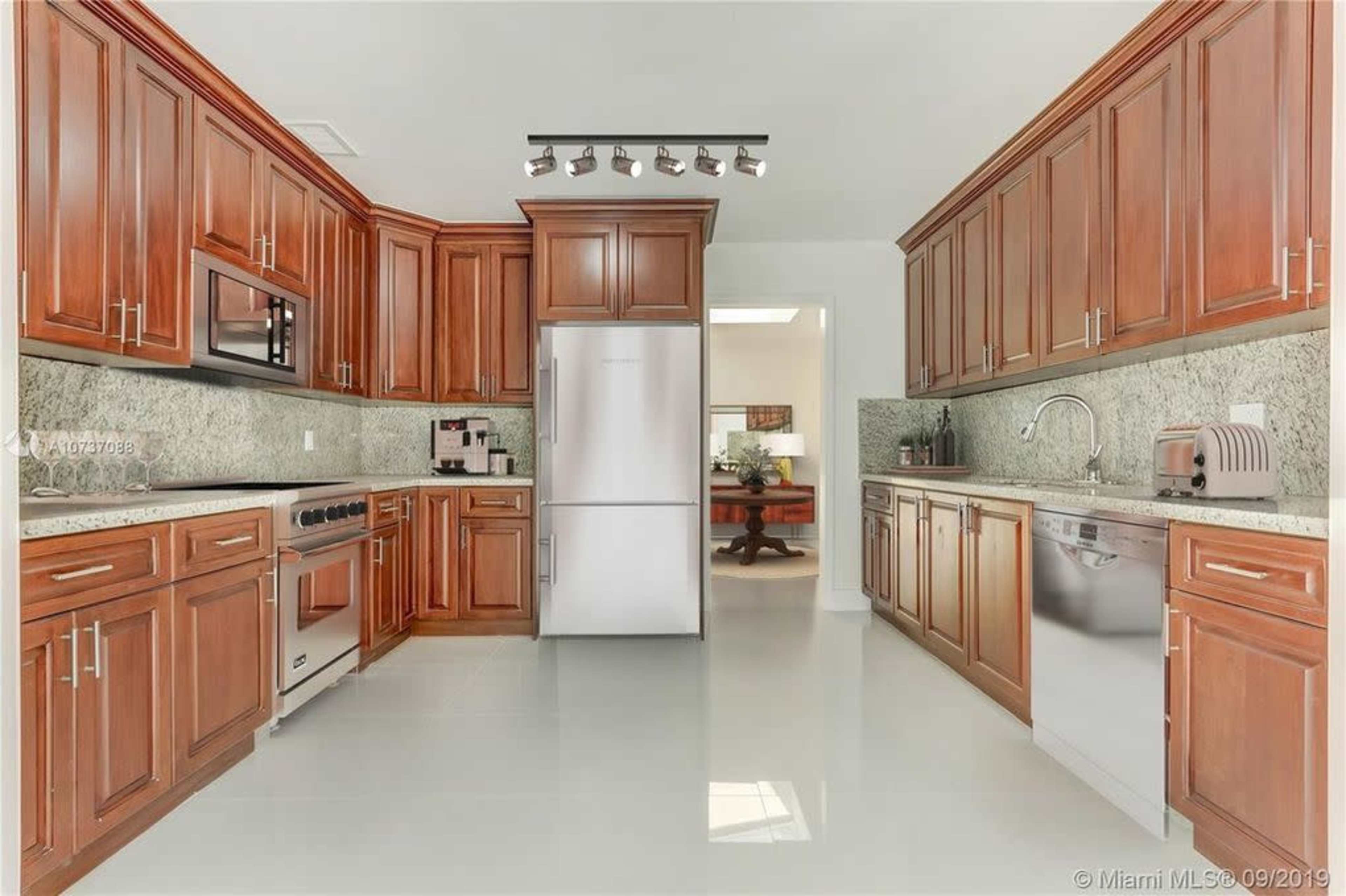 A modern kitchen with wooden cabinets, stainless steel appliances, and granite countertops.