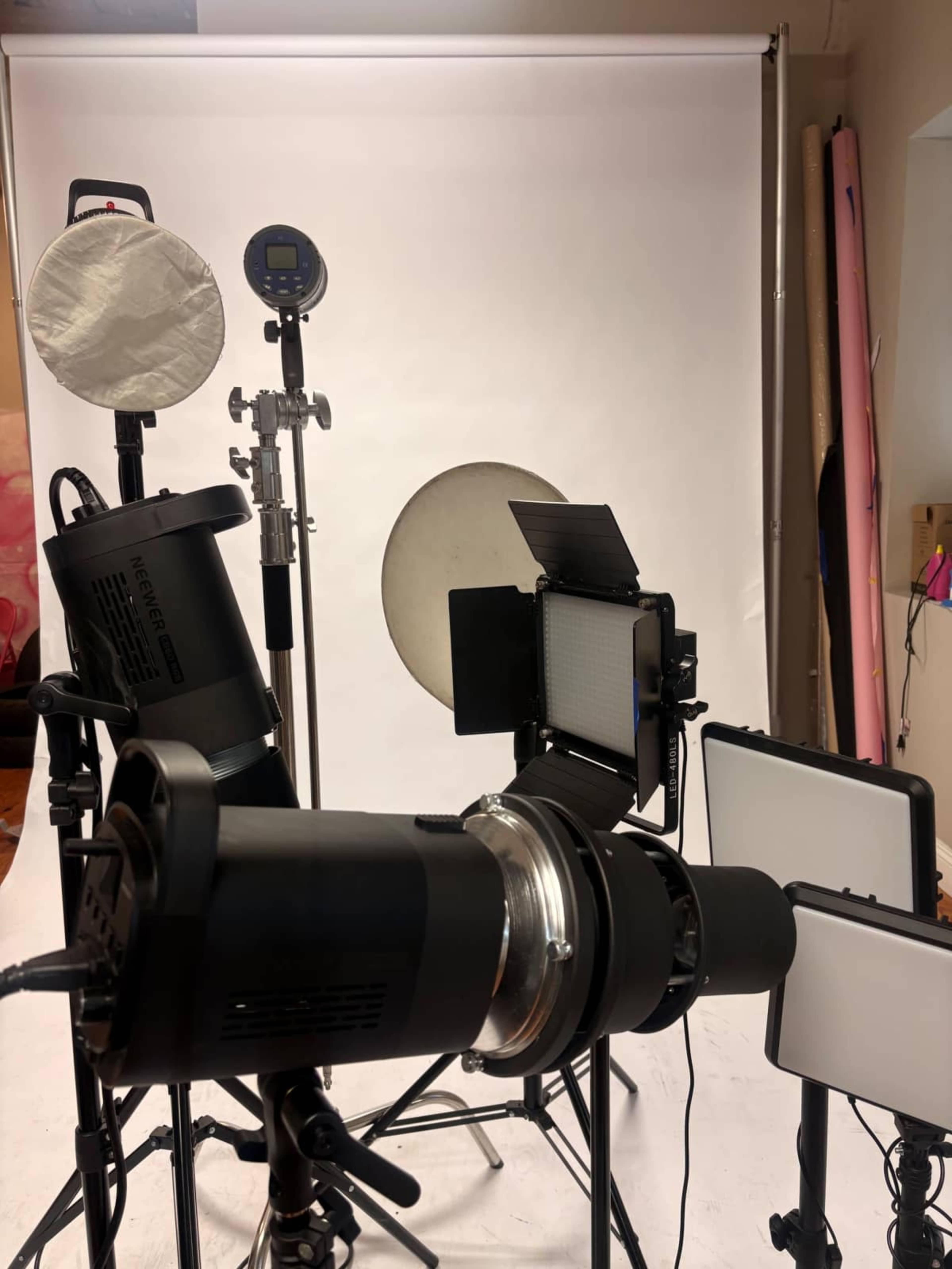 The image shows a collection of photography lighting equipment arranged in front of a plain backdrop.