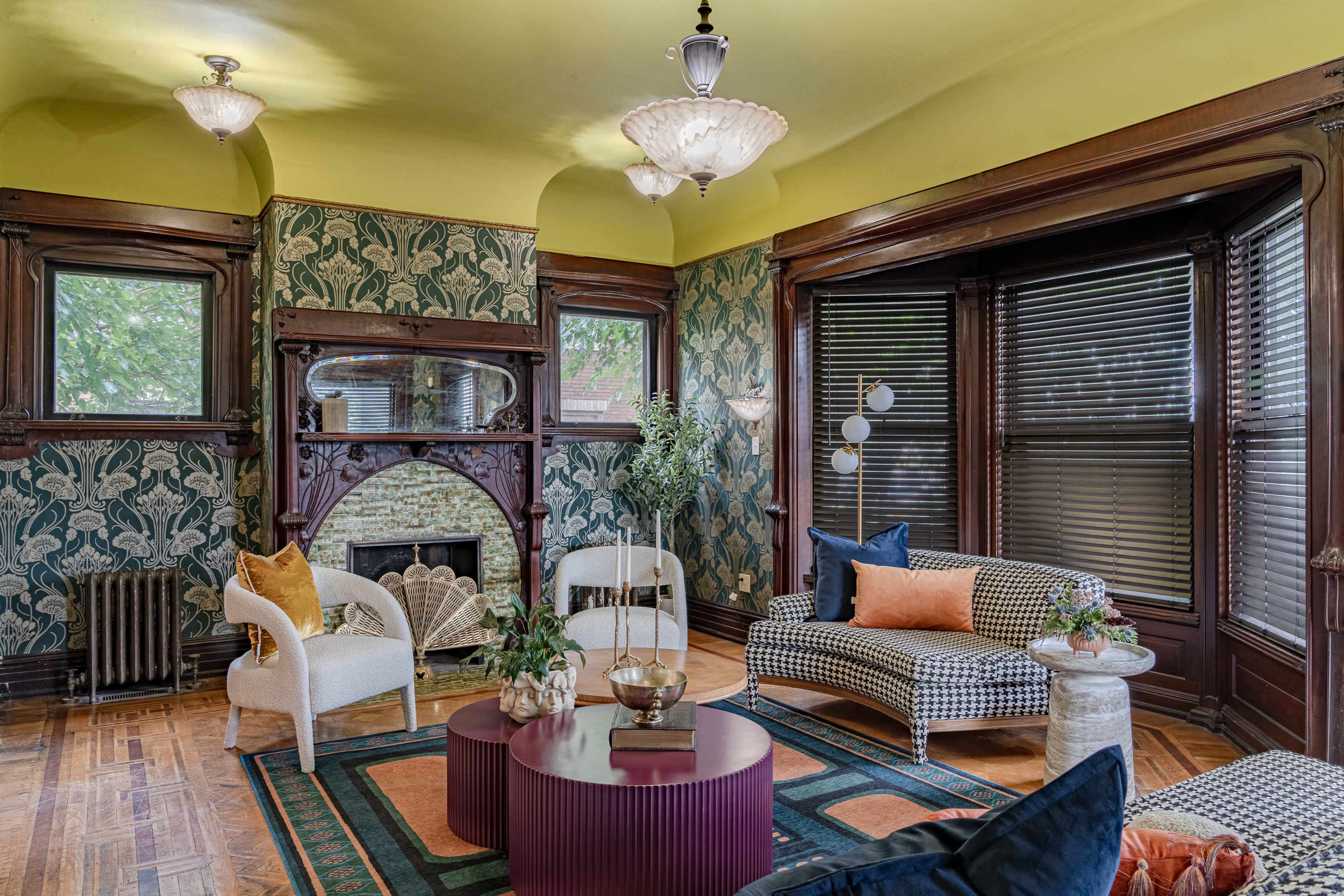 A vintage-style living room with patterned wallpaper, a decorative fireplace, and a mix of modern and classic furniture.