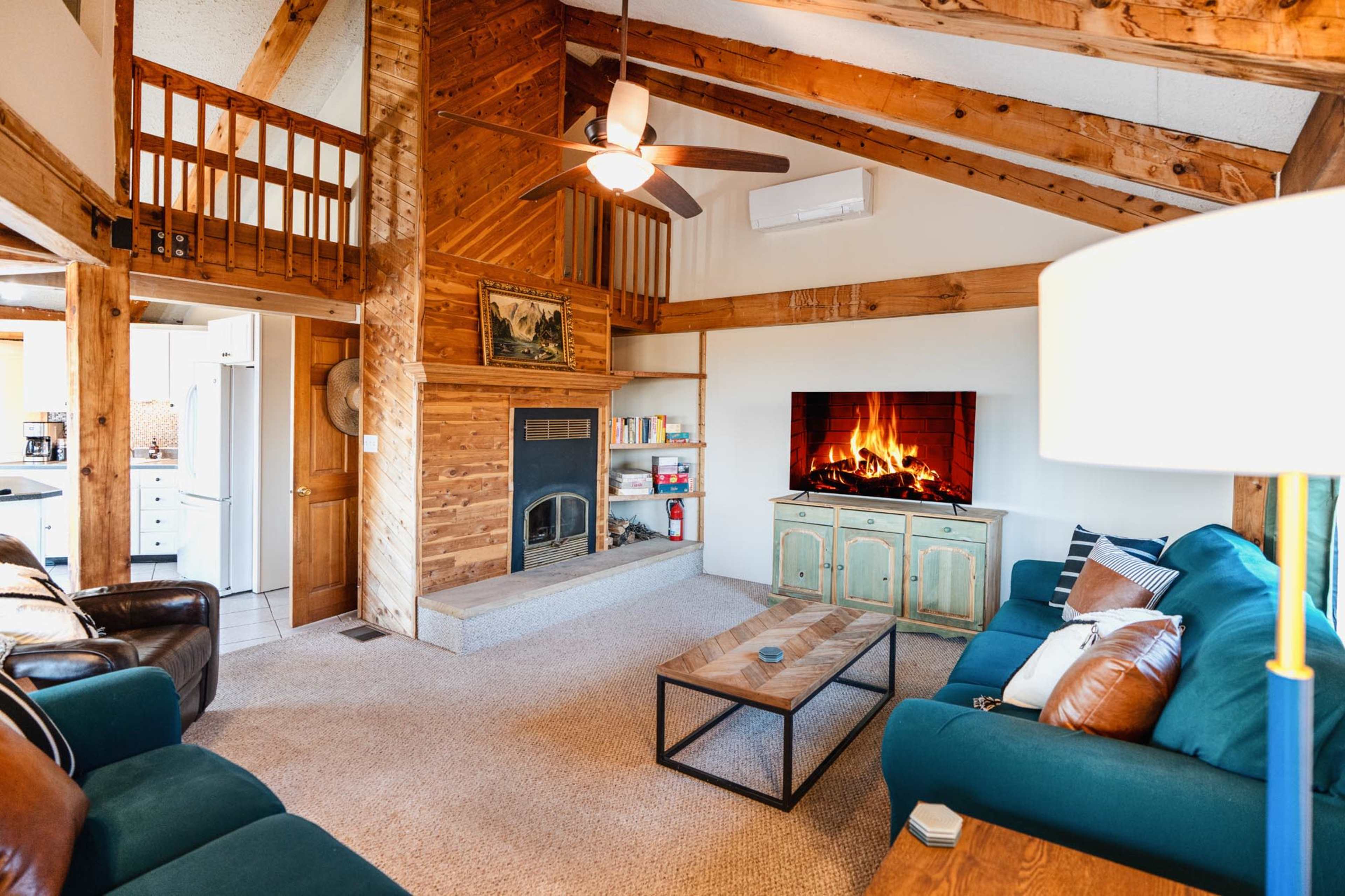 A rustic living room with wooden beams, a fireplace, and comfortable seating arranged around a central coffee table.