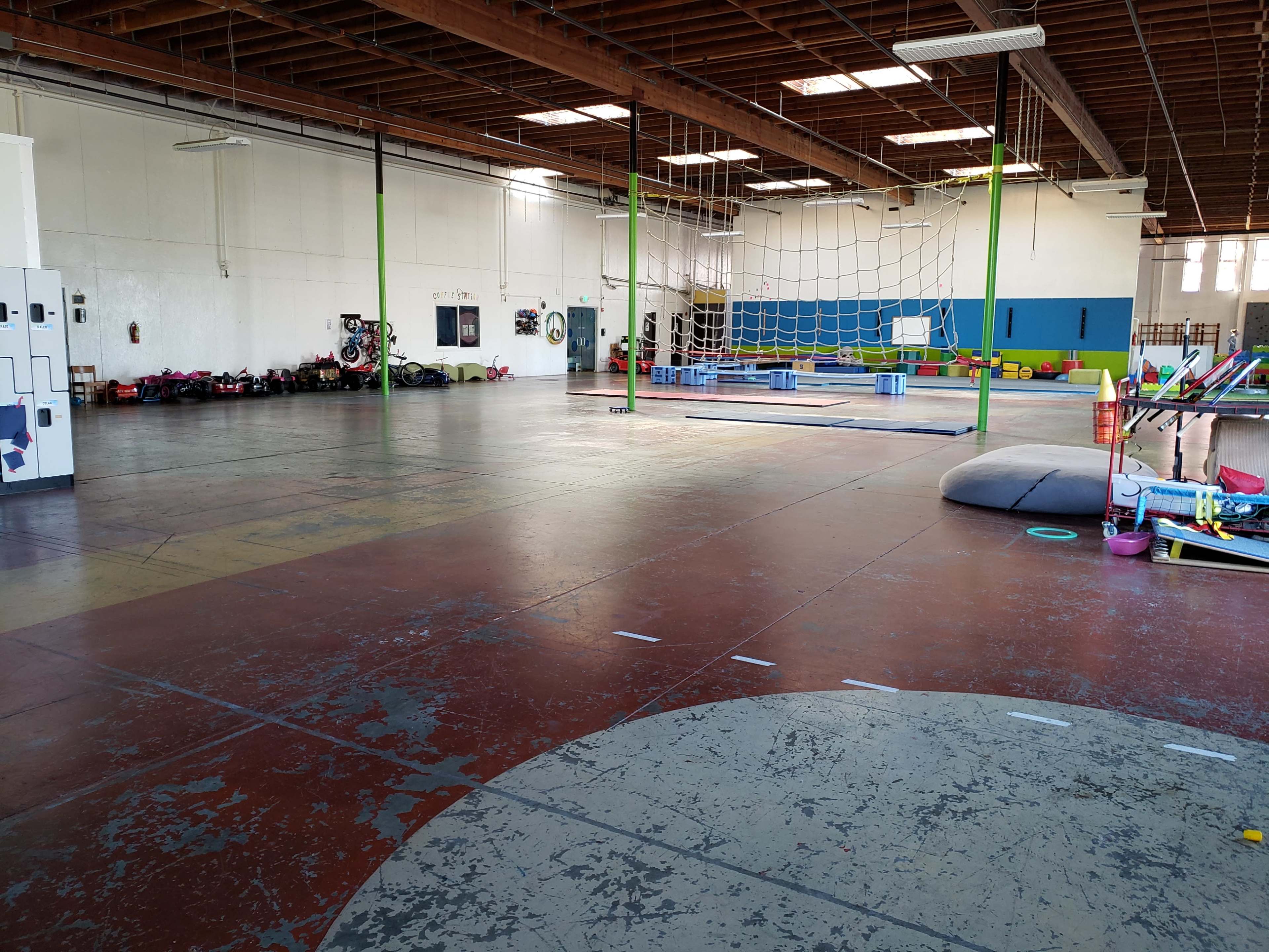 A spacious indoor gymnasium with a variety of play equipment and a large open floor area.