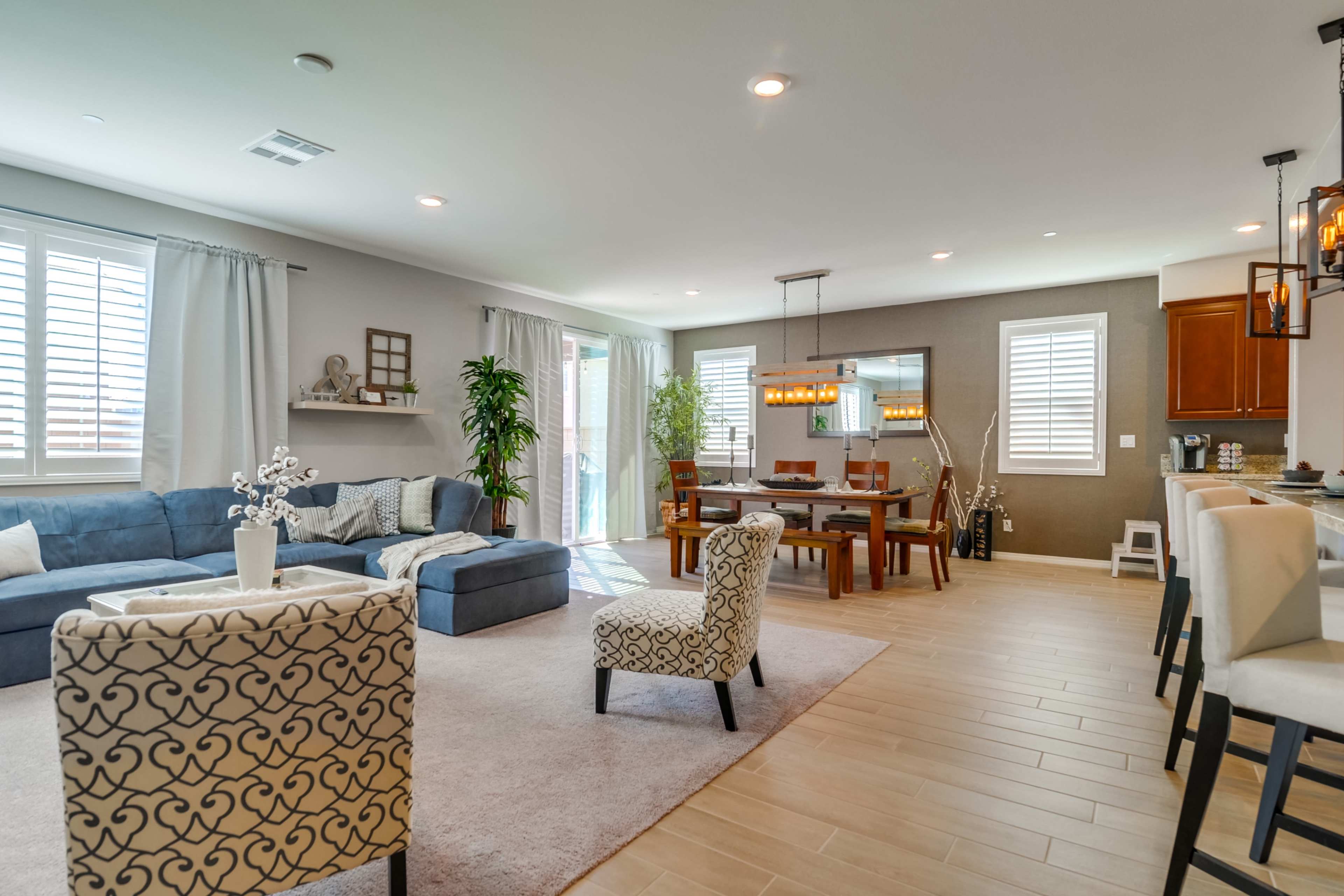 A spacious living room features a blue sofa, a dining area with a wooden table, and modern decor throughout.