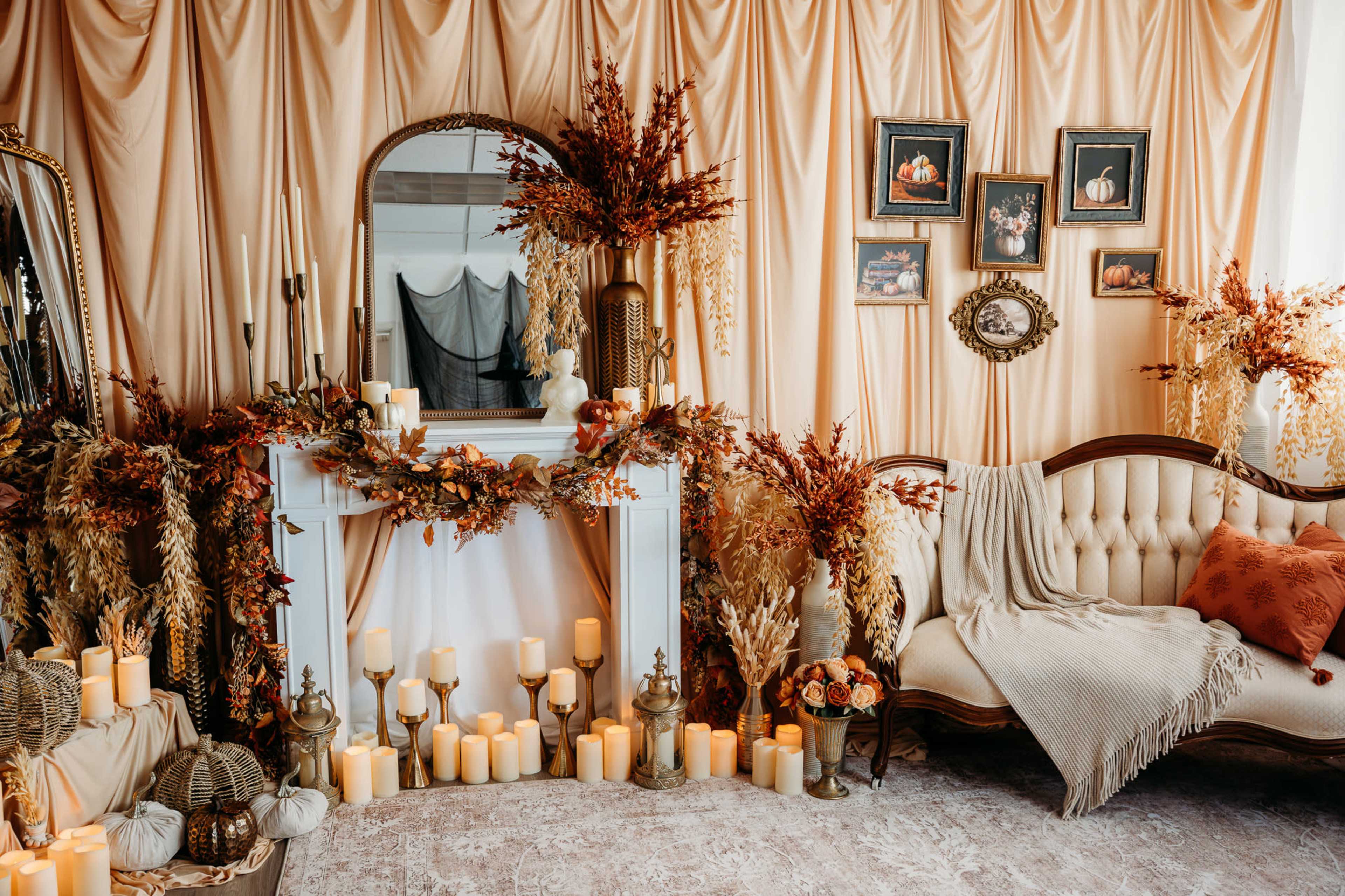 The image features a warm-toned interior with a decorated fireplace, adorned with autumn foliage, candles, and a vintage sofa, creating a cozy atmosphere.