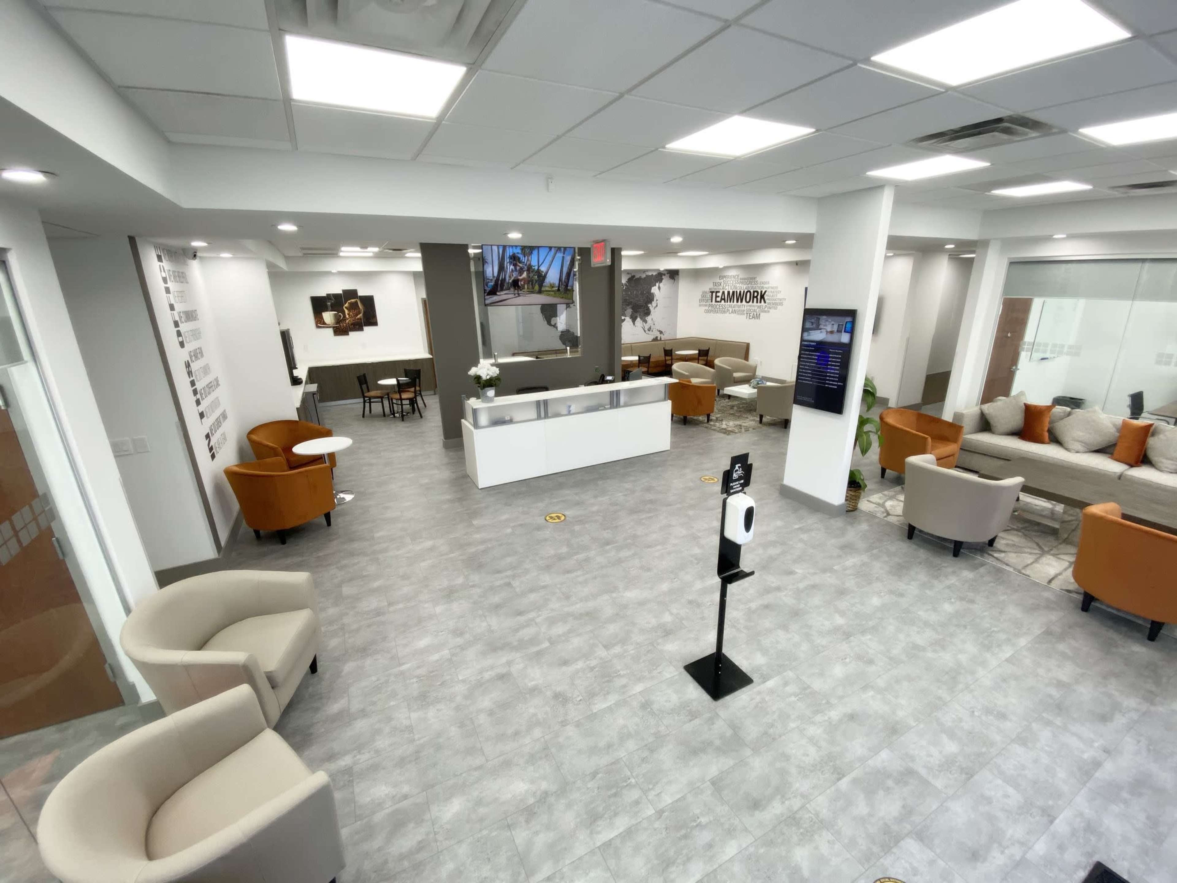 A modern office reception area with seating, a front desk, and a large wall map in the background.