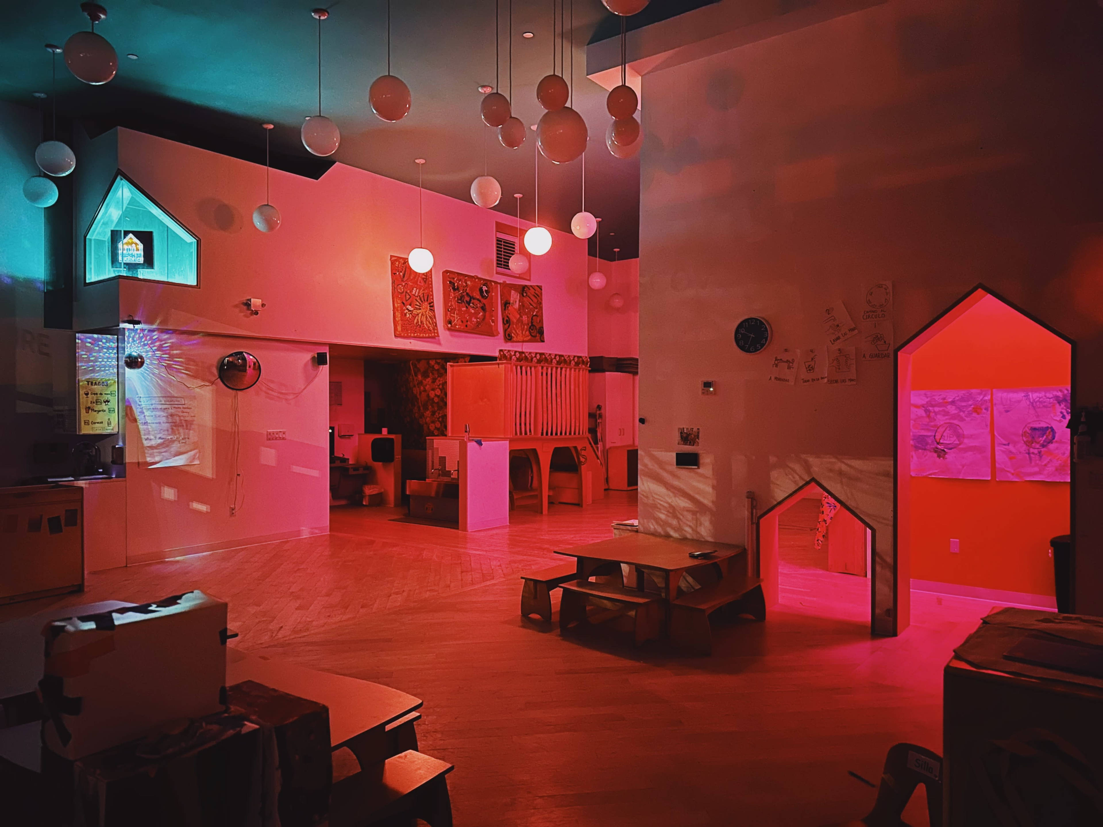 A brightly colored room with various seating arrangements, walls decorated with children's artwork, and warm lighting creating a vibrant atmosphere.