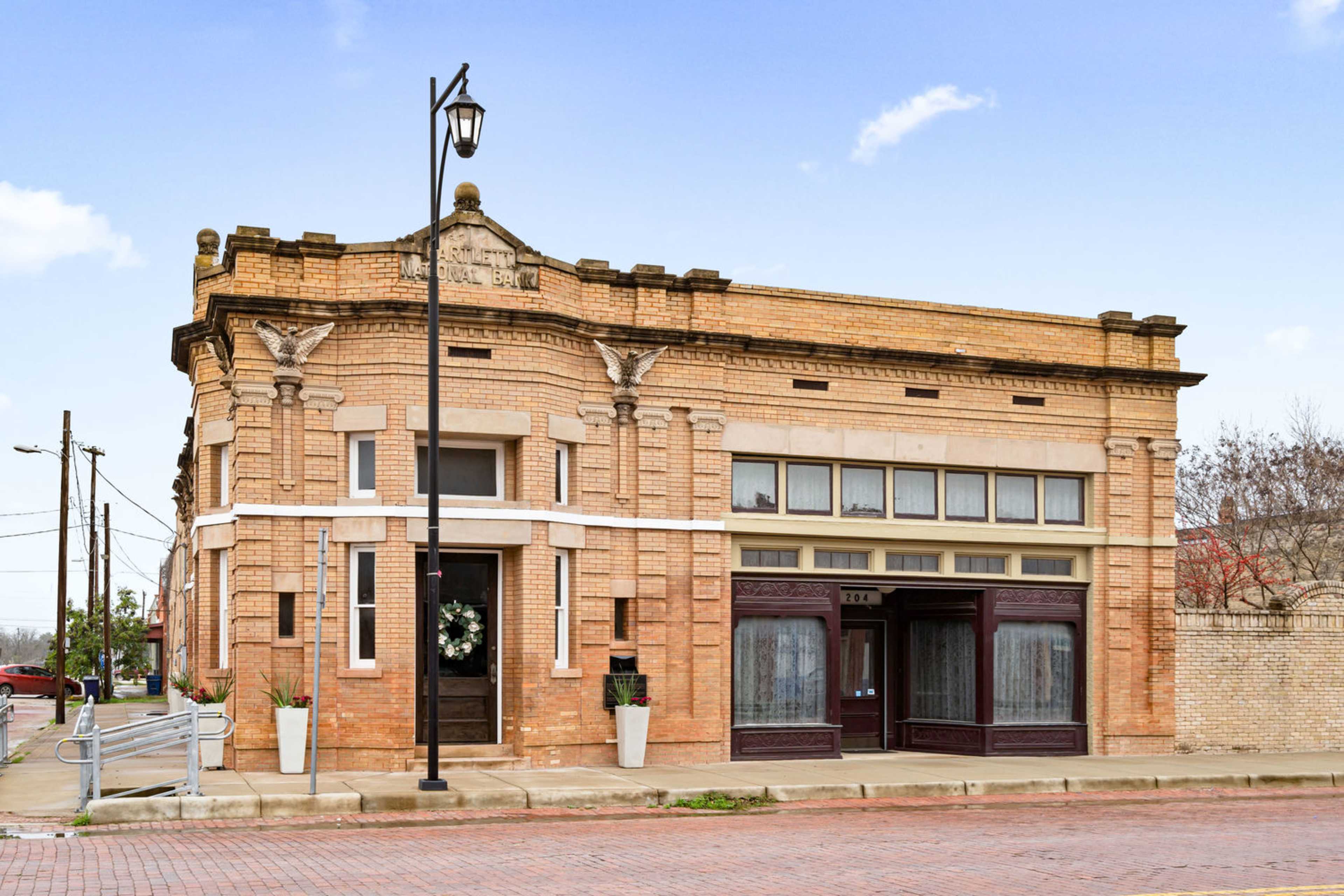 A vintage brick building with decorative elements and large windows, situated on a street corner.