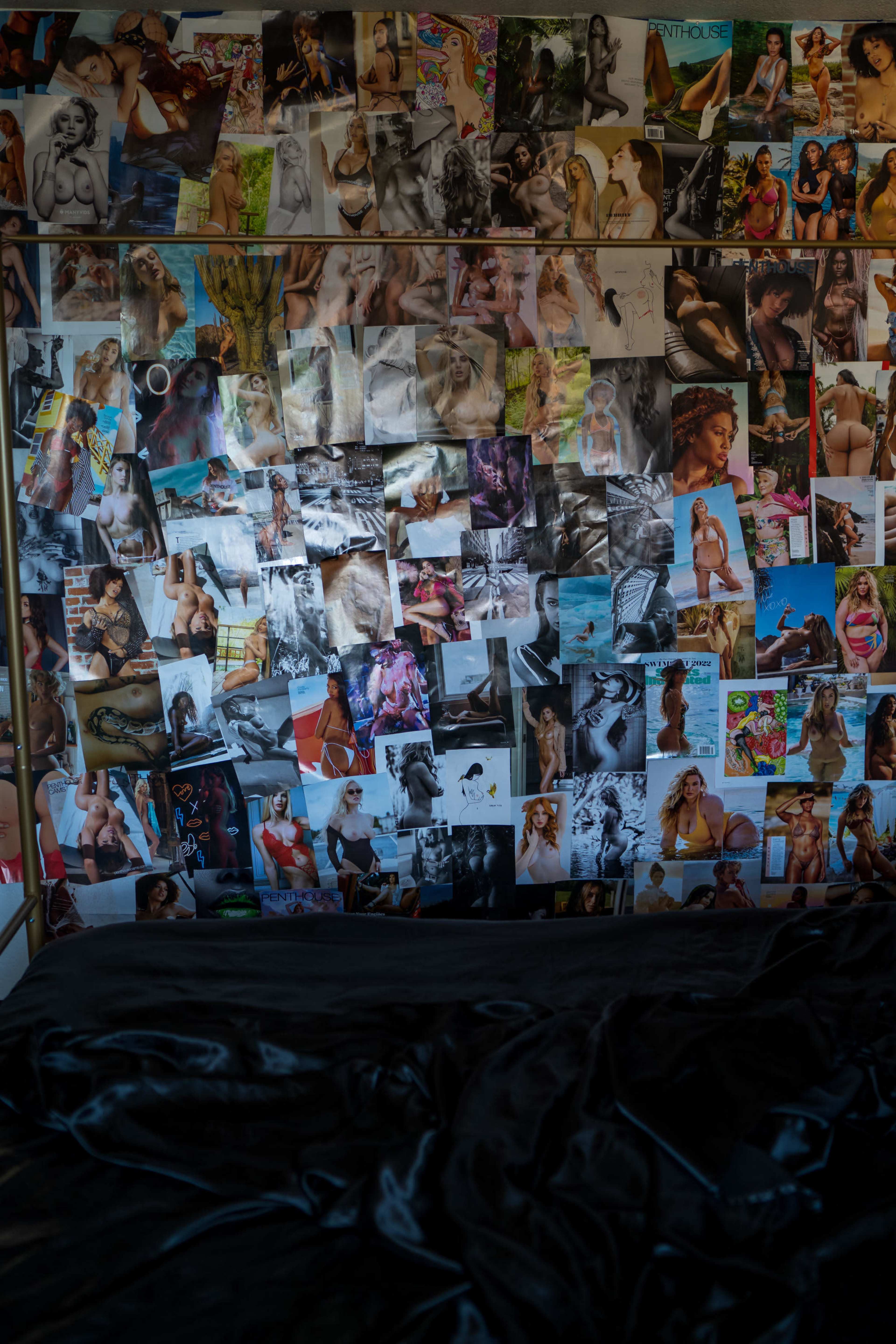 A black bedspread is shown in the foreground in front of a wall covered with a collage of photographs featuring various individuals.