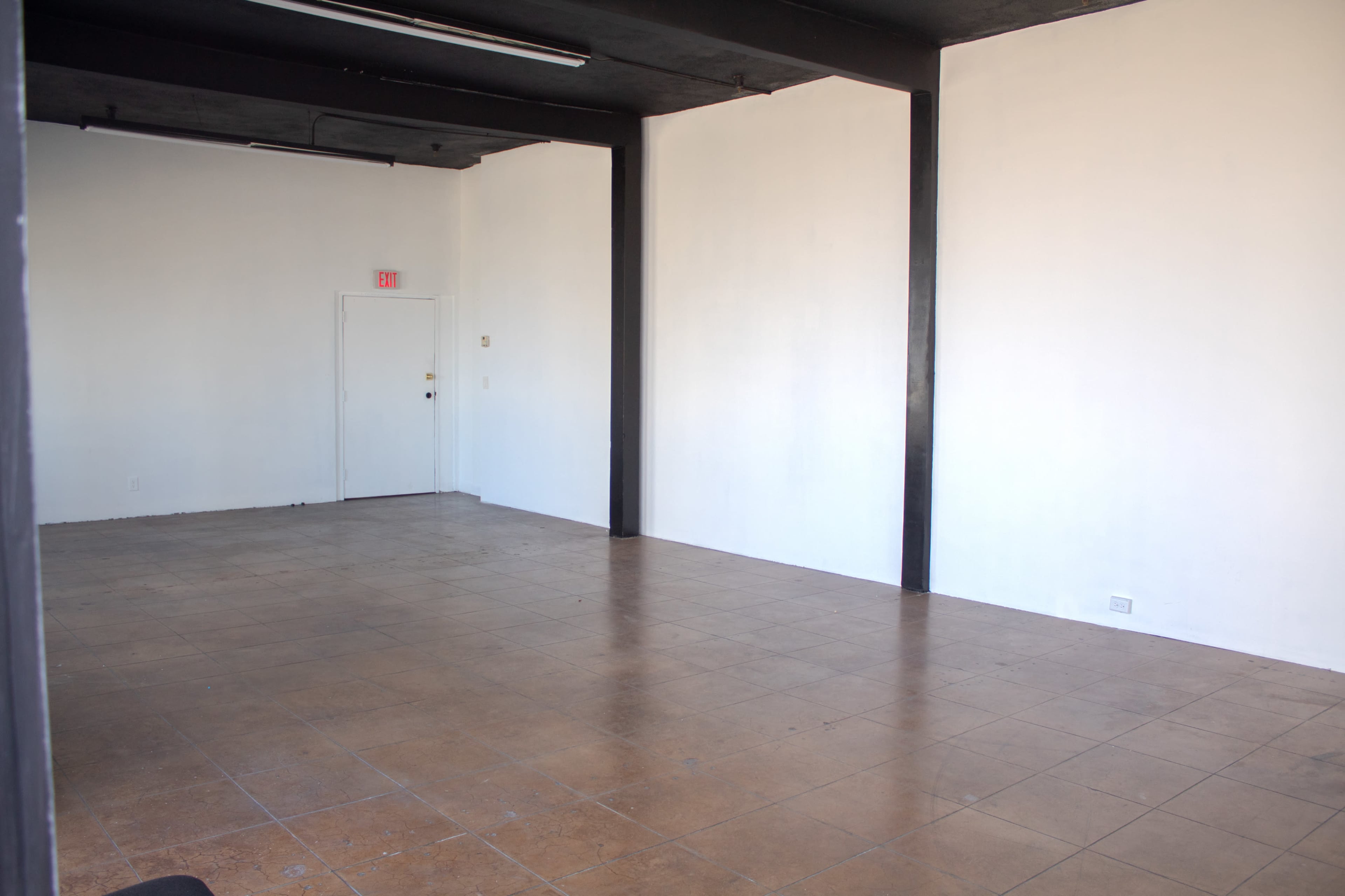 The image shows an empty room with white walls, a door, and tiled floors.