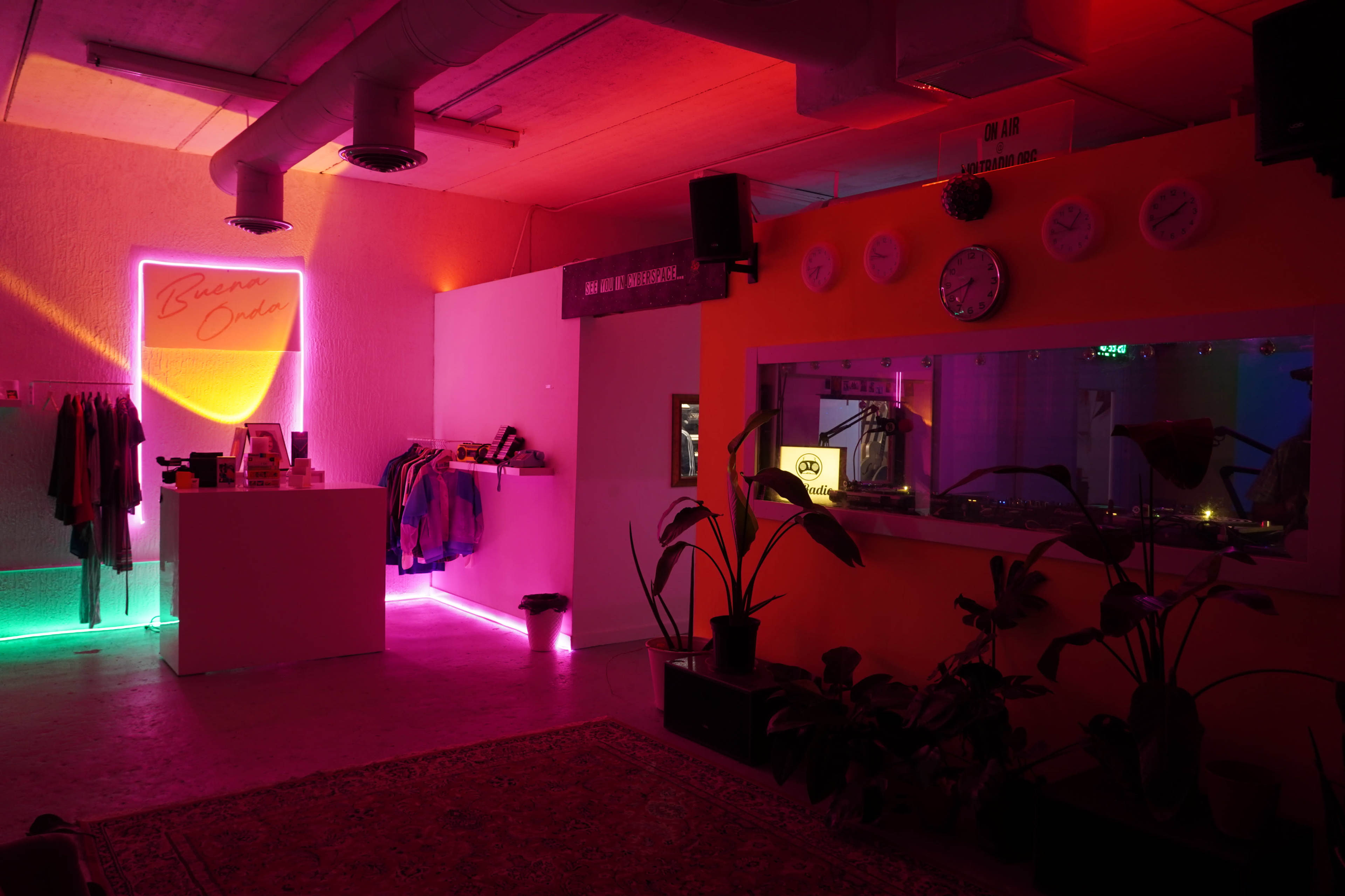 A modern retail space featuring colorful neon lights, clothing racks, and decorative plants.