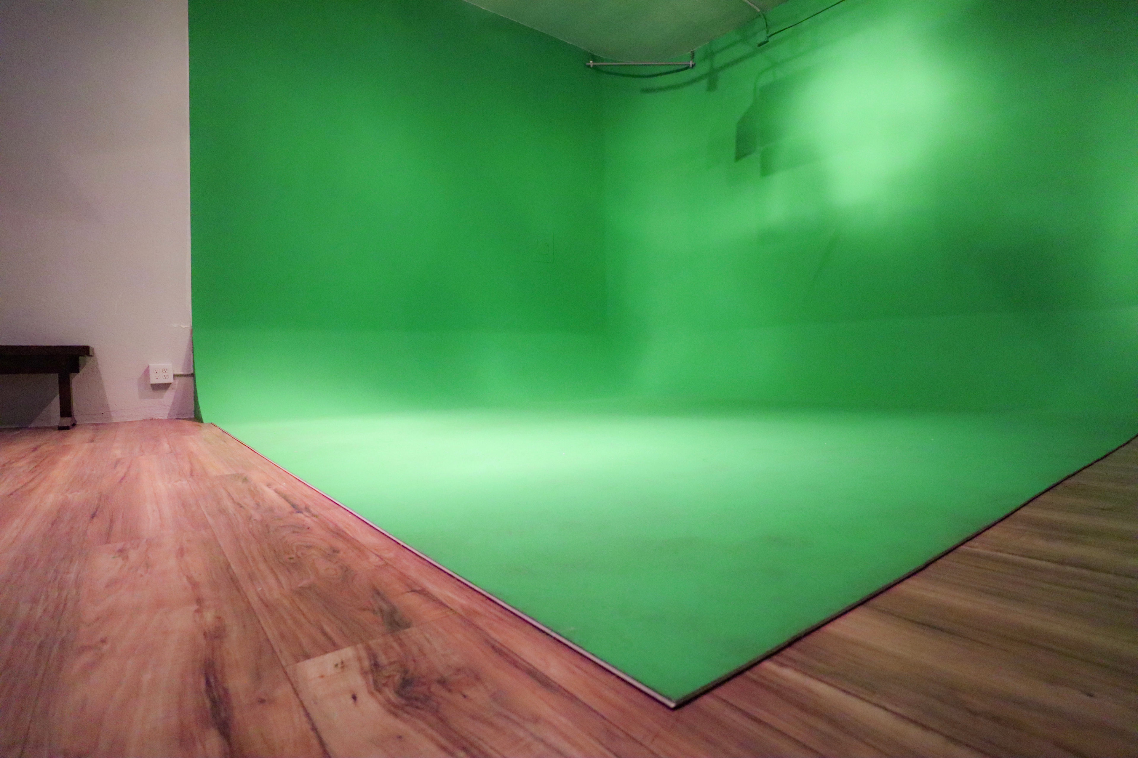 The image shows a room with a green backdrop and a wooden floor.
