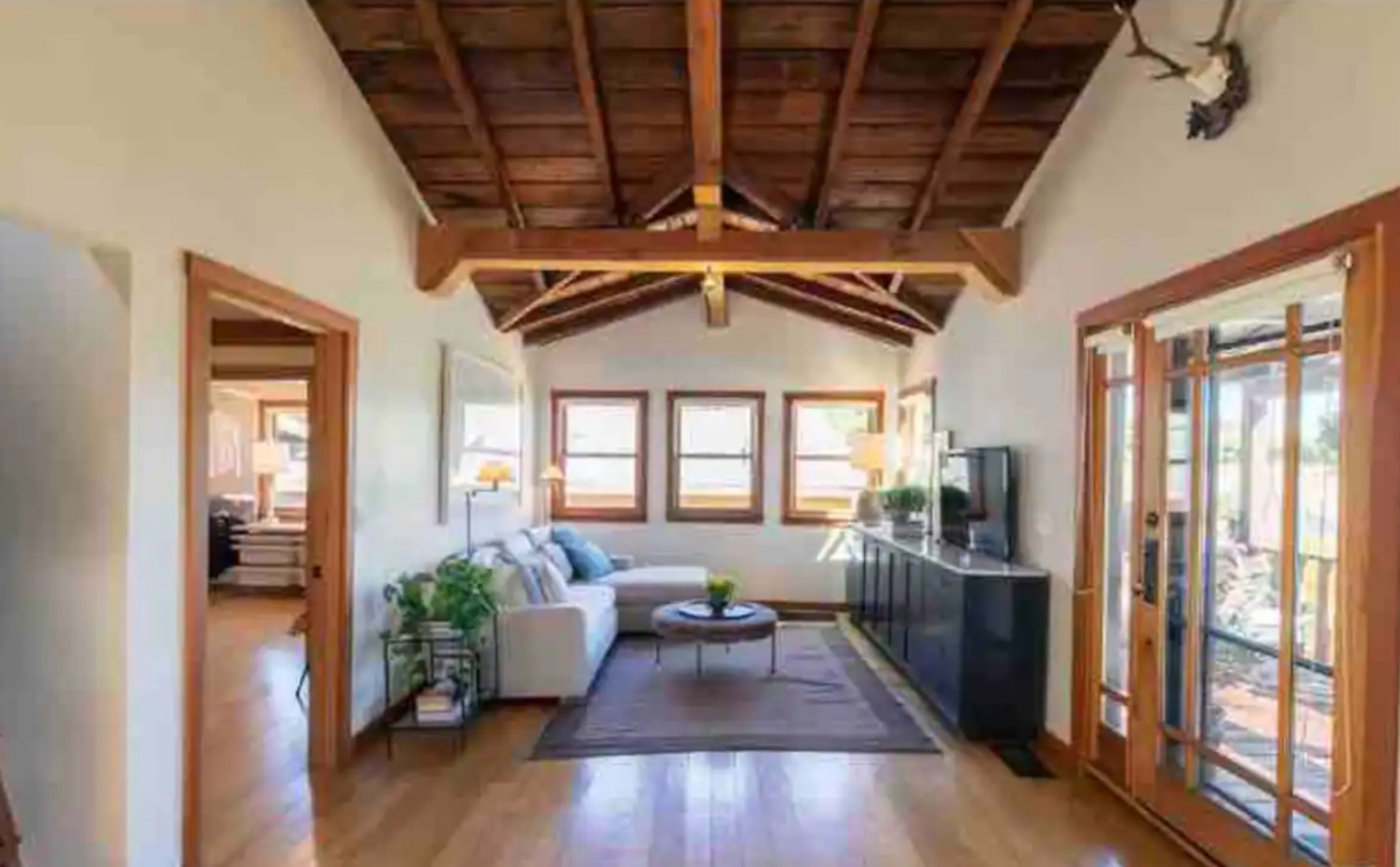A living room featuring a white sectional sofa, a coffee table with a small plant, and large windows that allow natural light to enter.