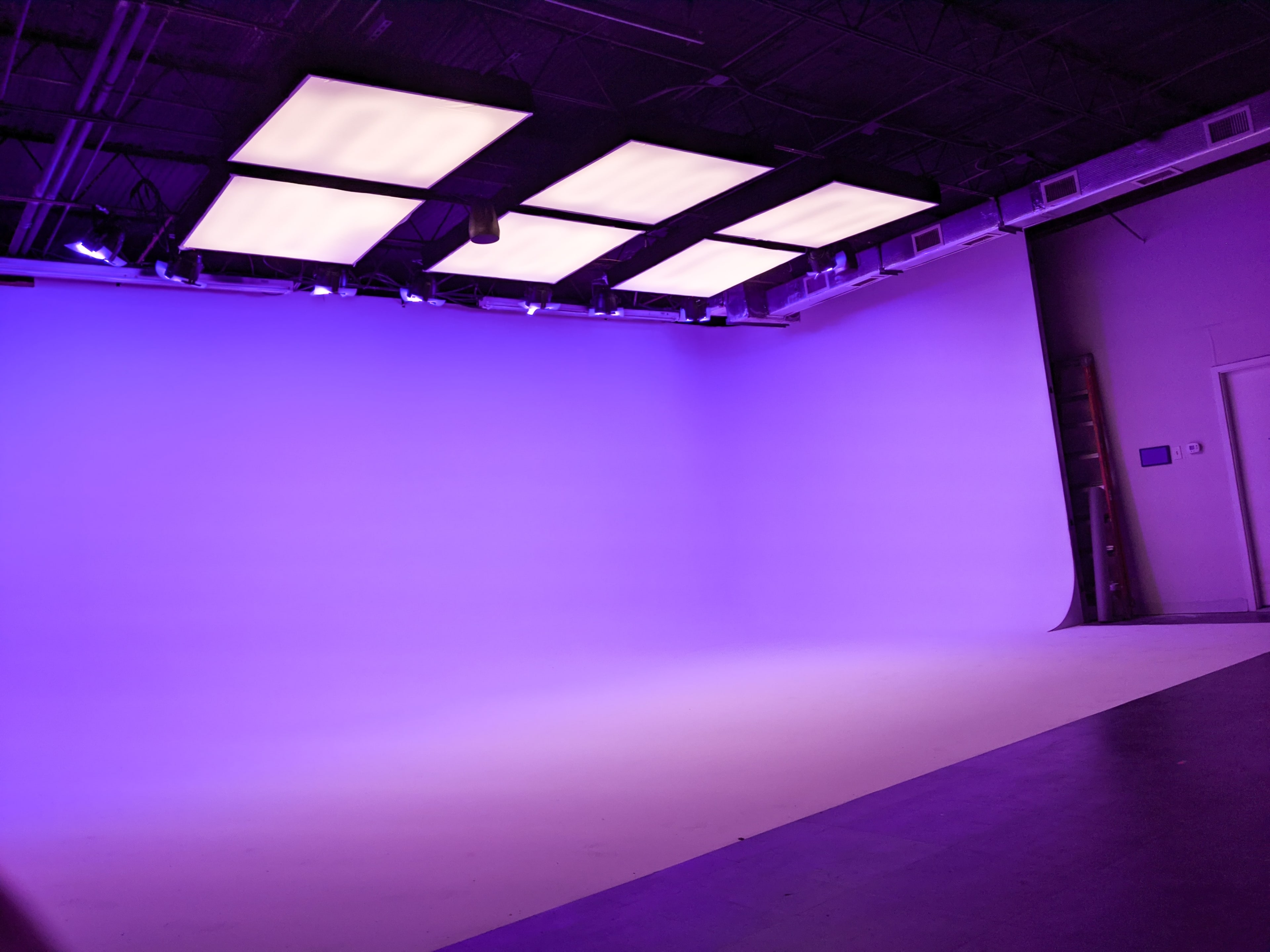 A photography studio featuring a smooth purple backdrop and bright ceiling lights.