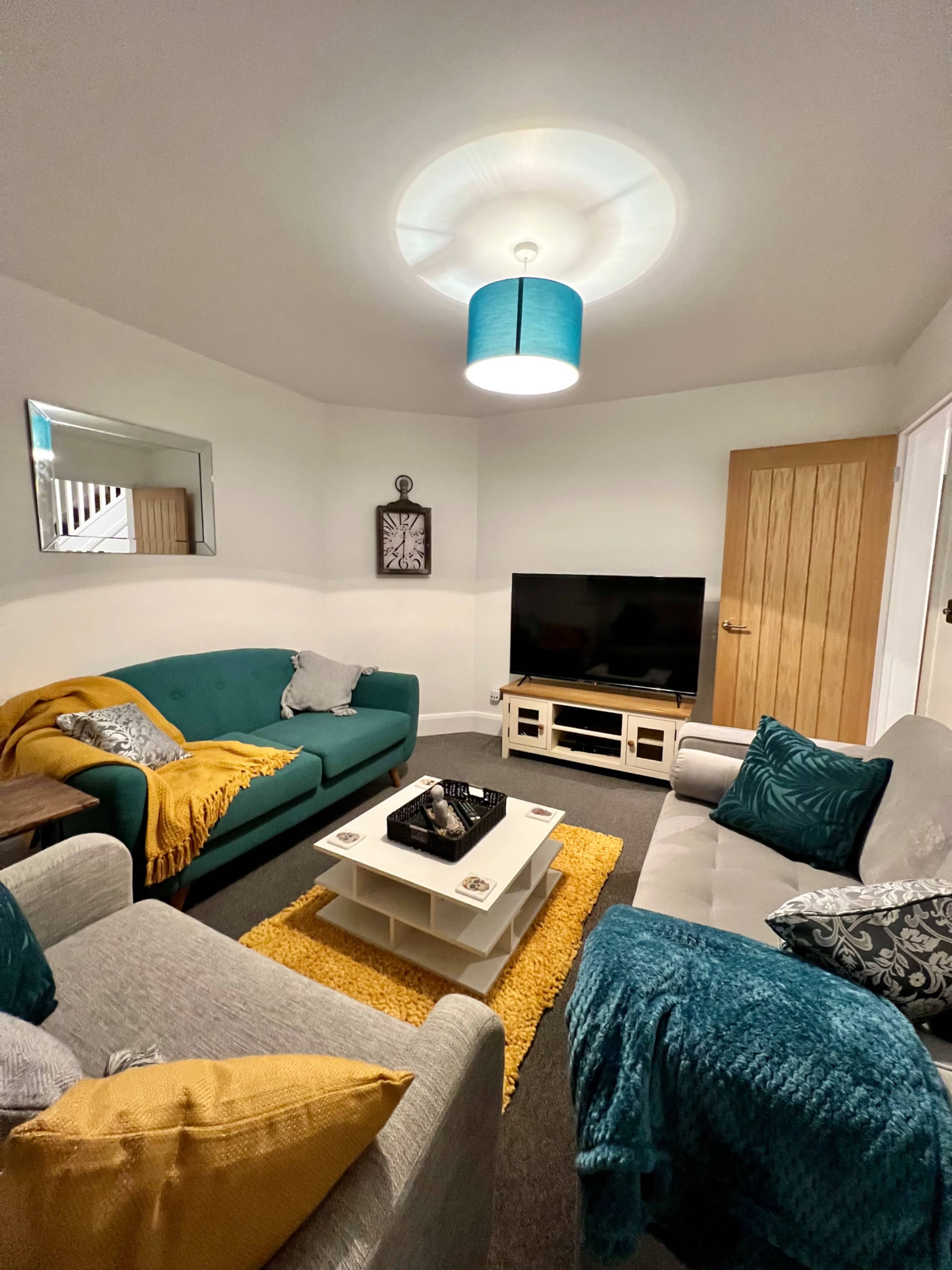 A cozy living room features two sofas, a coffee table, a television, and decorative items against neutral walls.