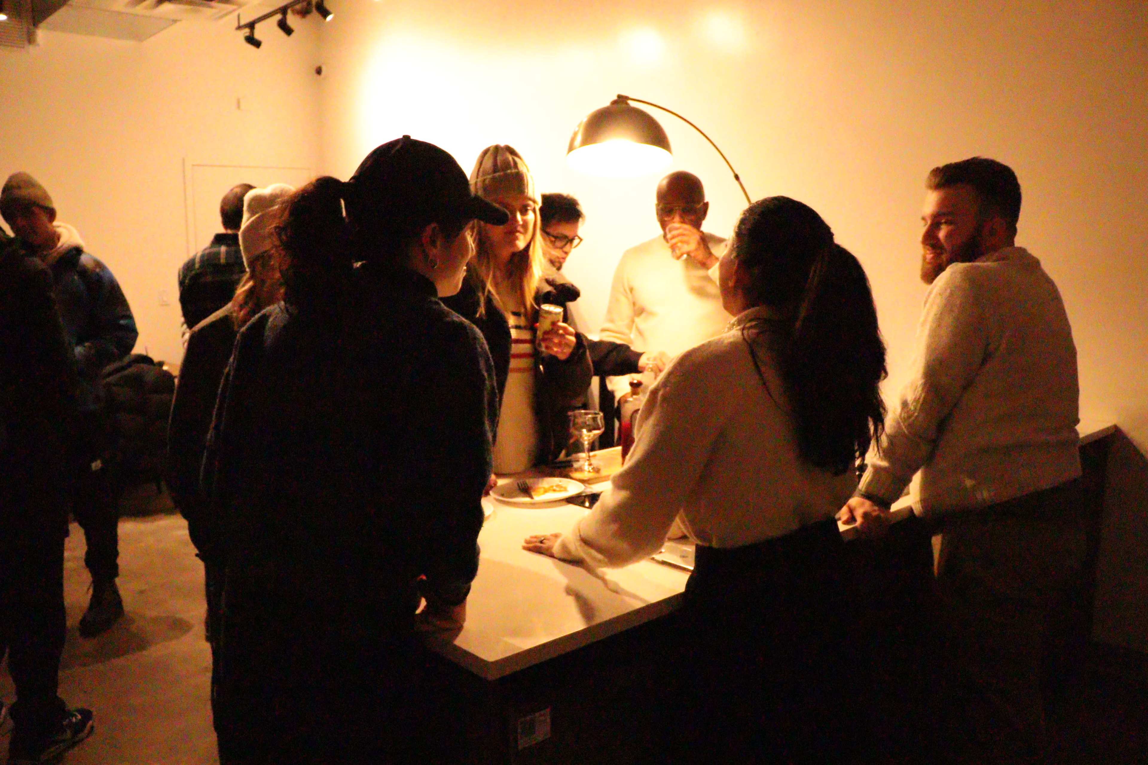 A group of people engages in conversation around a table in a dimly lit room.