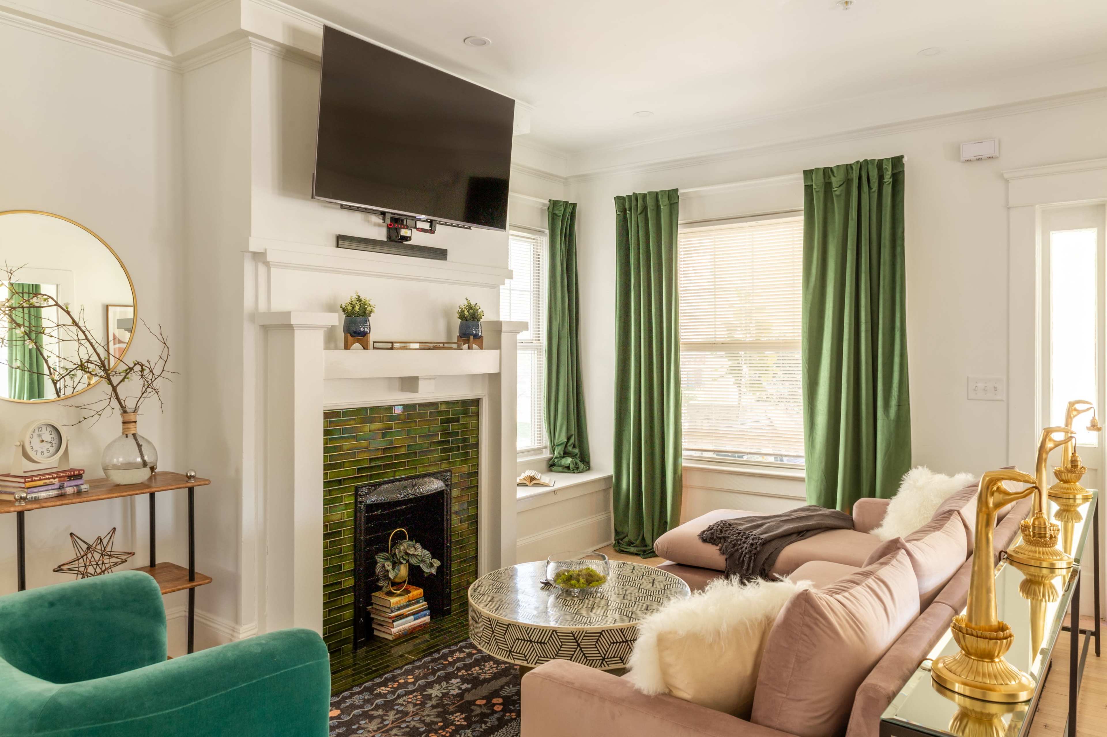 A living room with a green and white color scheme, featuring a flat-screen TV above a fireplace, a coffee table, and a sofa arranged for seating.