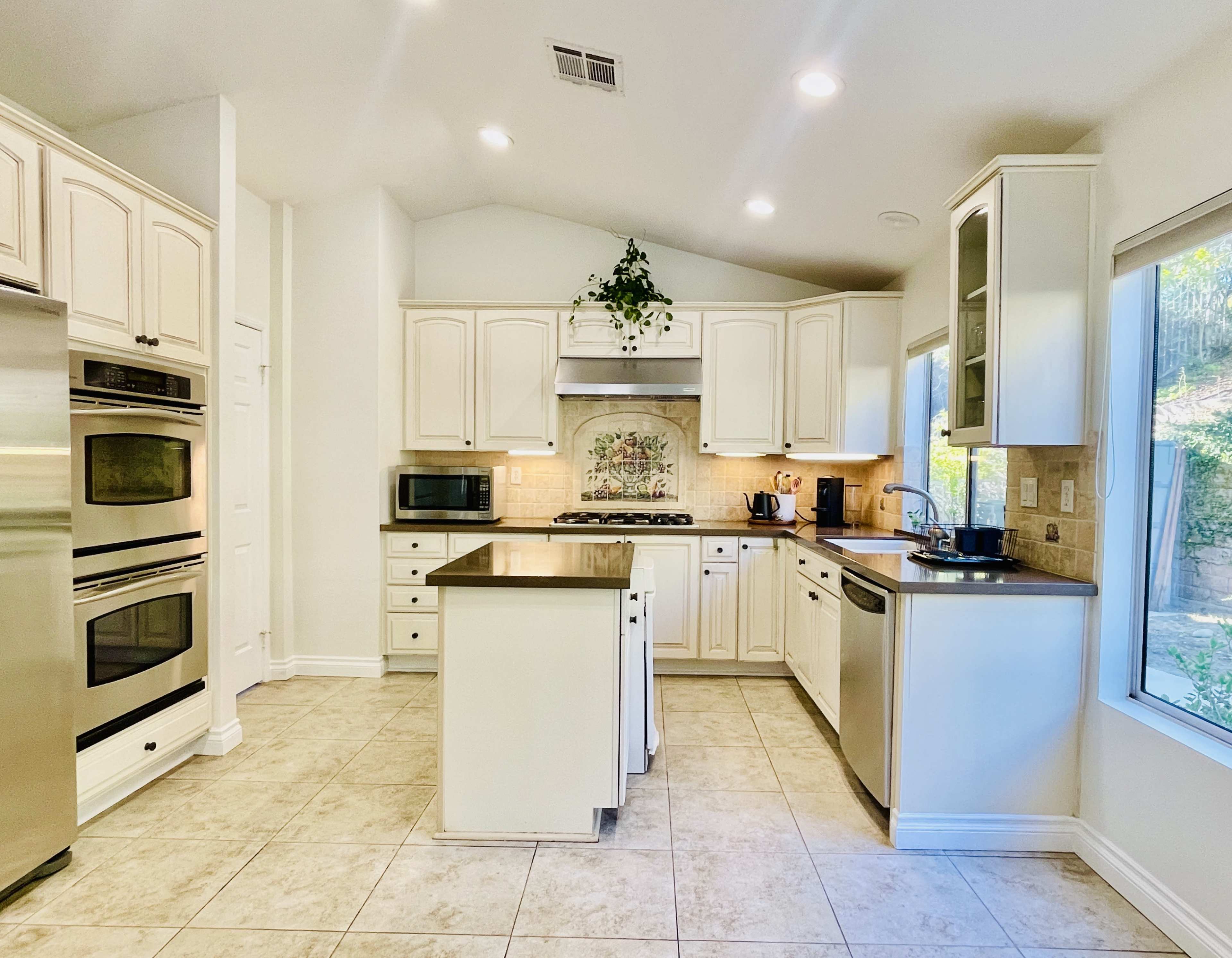 A bright kitchen features white cabinetry, stainless steel appliances, and a central island with a countertop.