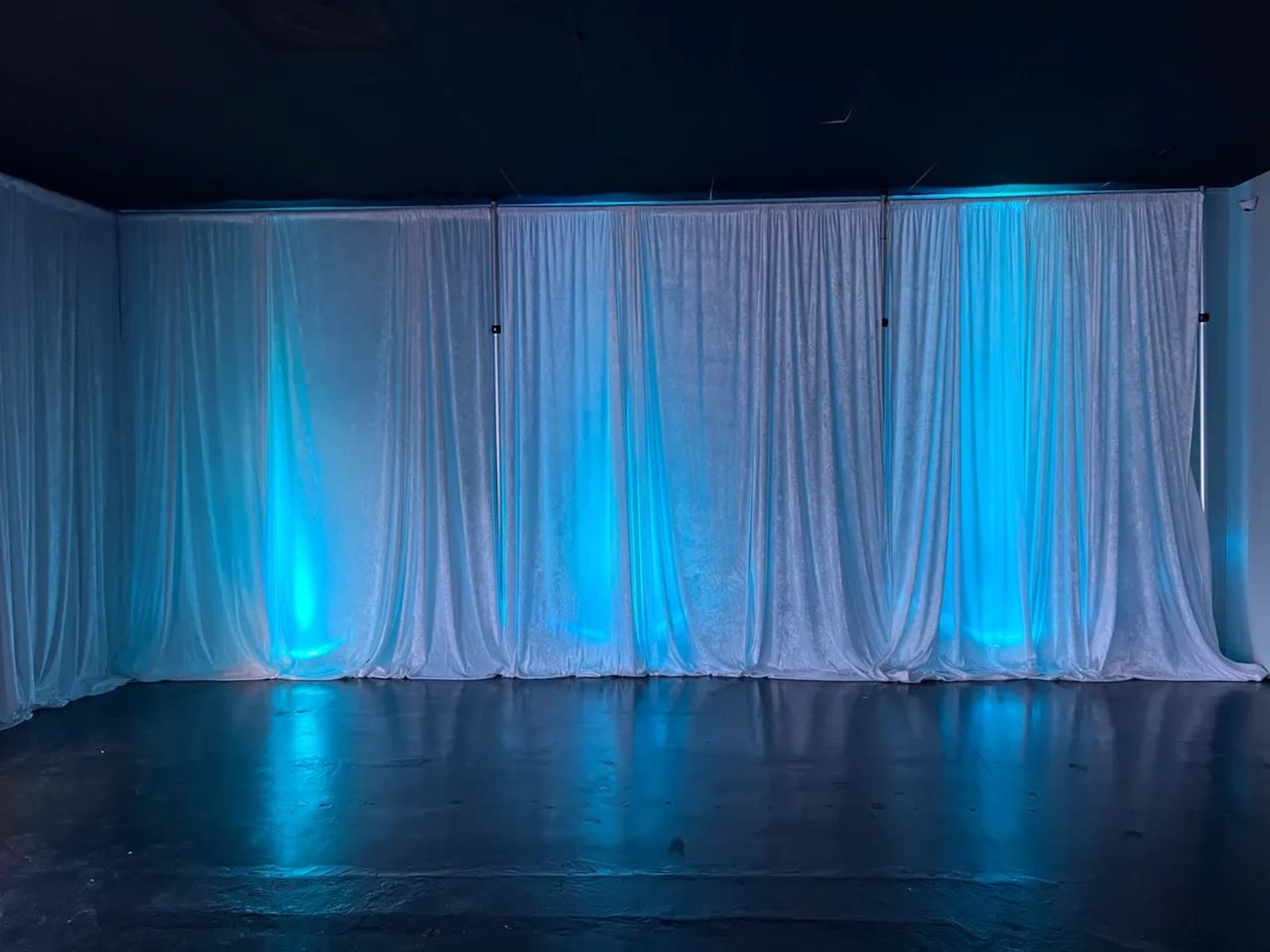 A room with white draped curtains illuminated by blue lights.