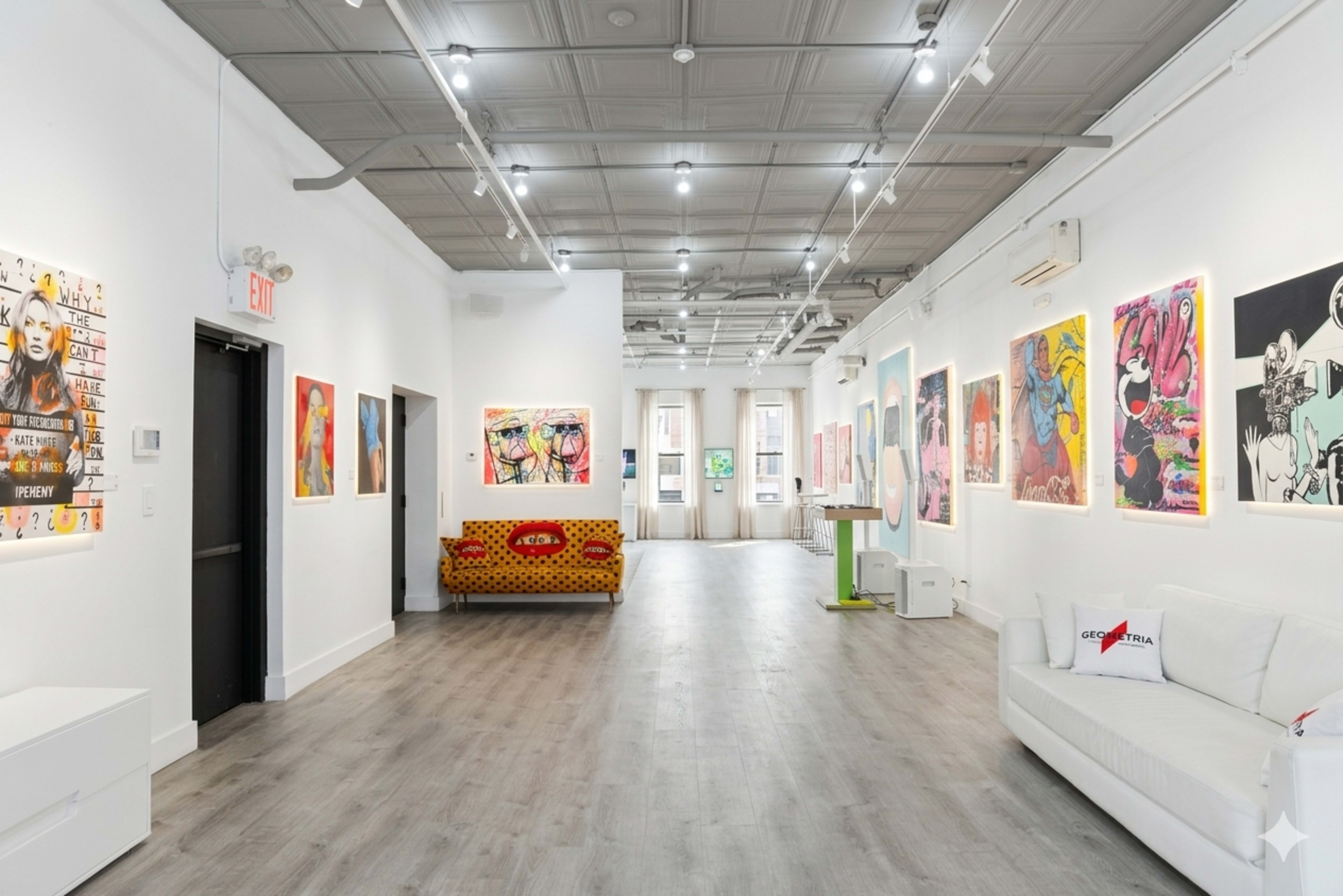 The image depicts a modern art gallery featuring various colorful artworks on the walls and a seating area with a patterned sofa.