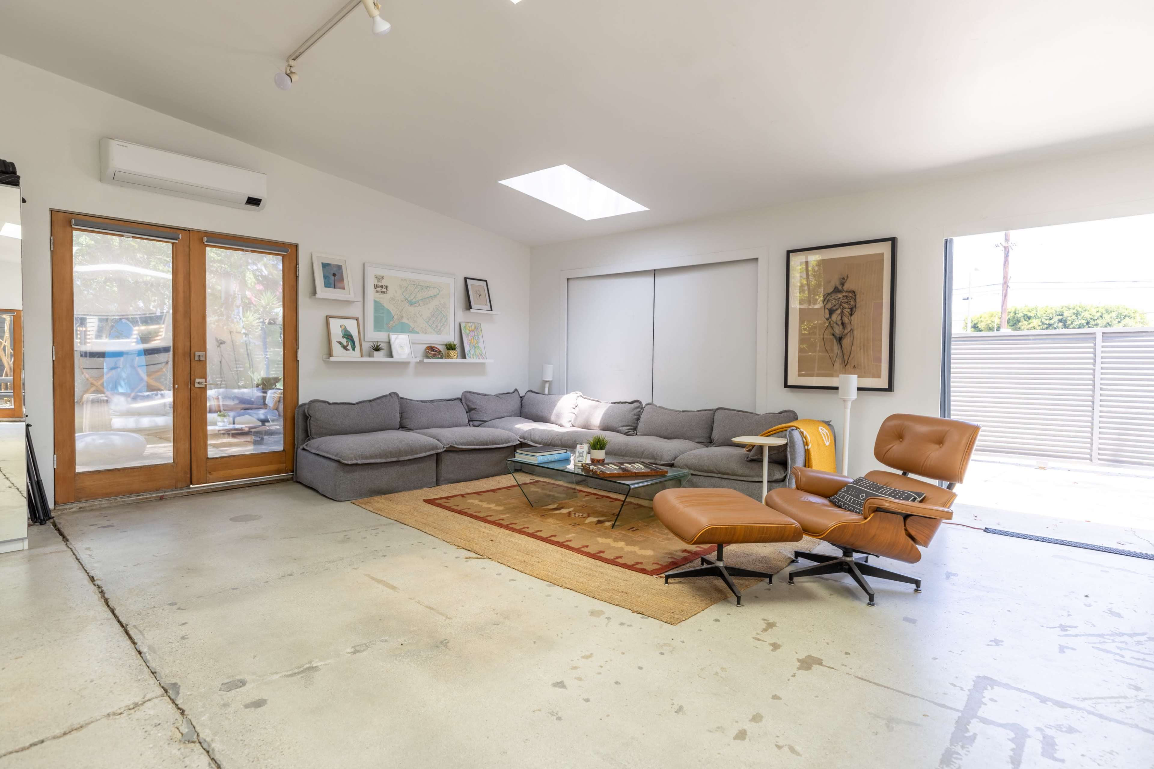 A modern living room with a gray sectional sofa, a brown lounge chair, and large glass doors leading to an outdoor area.