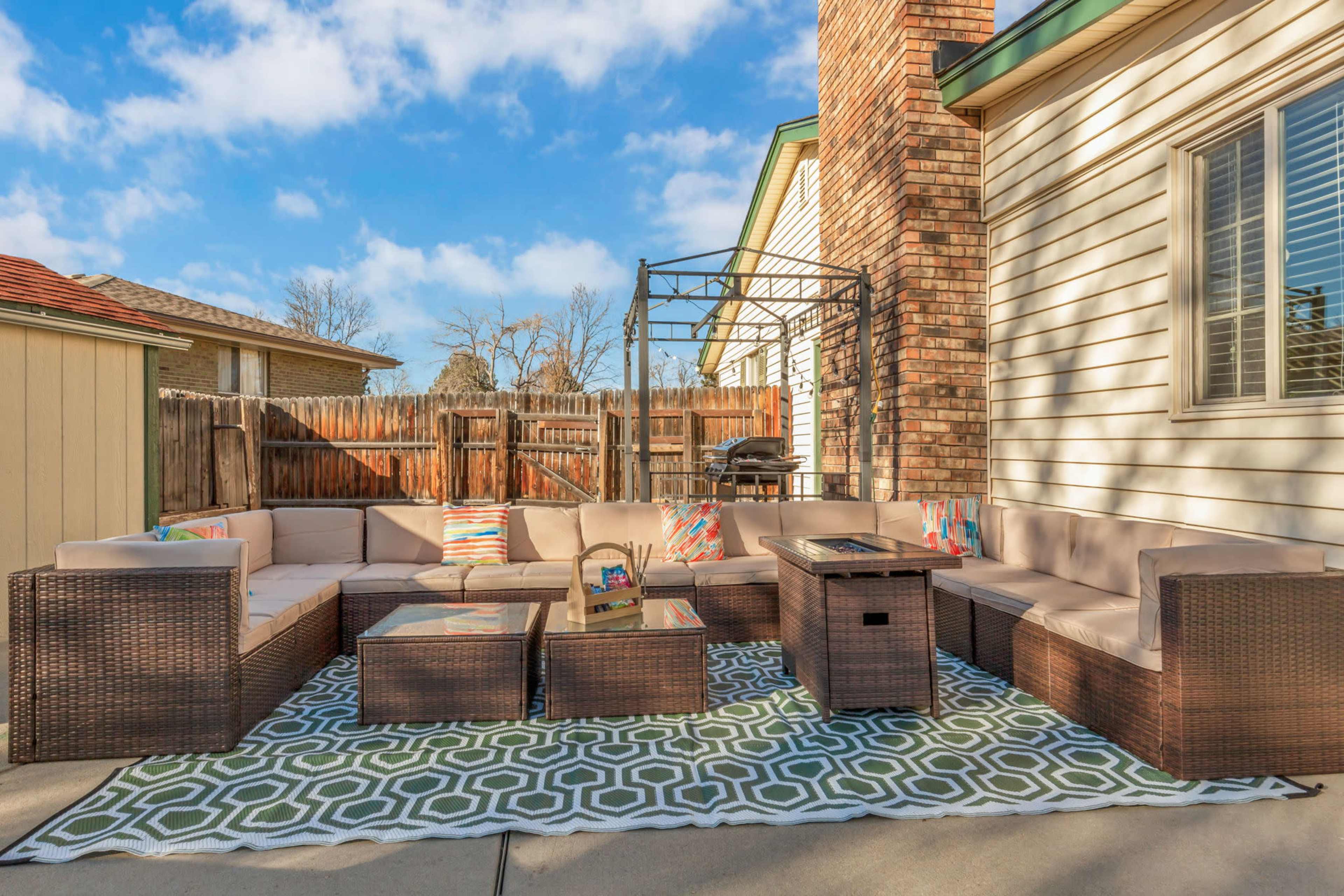 A patio area features a large sectional sofa, several coffee tables, and a gazebo, set against a backdrop of a wooden fence and houses.