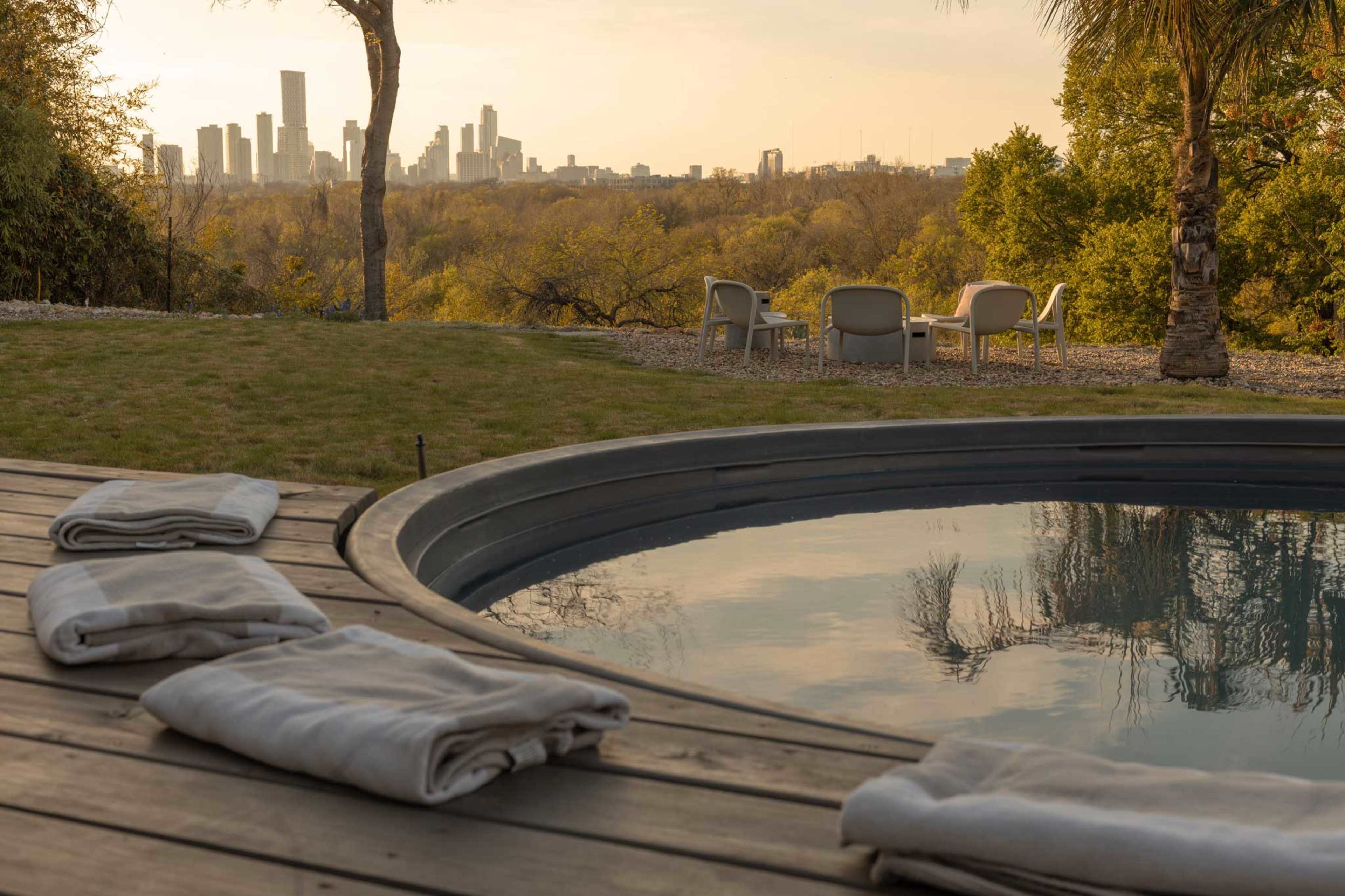 A view of a city skyline is seen from a backyard with a swimming pool and lounge chairs.