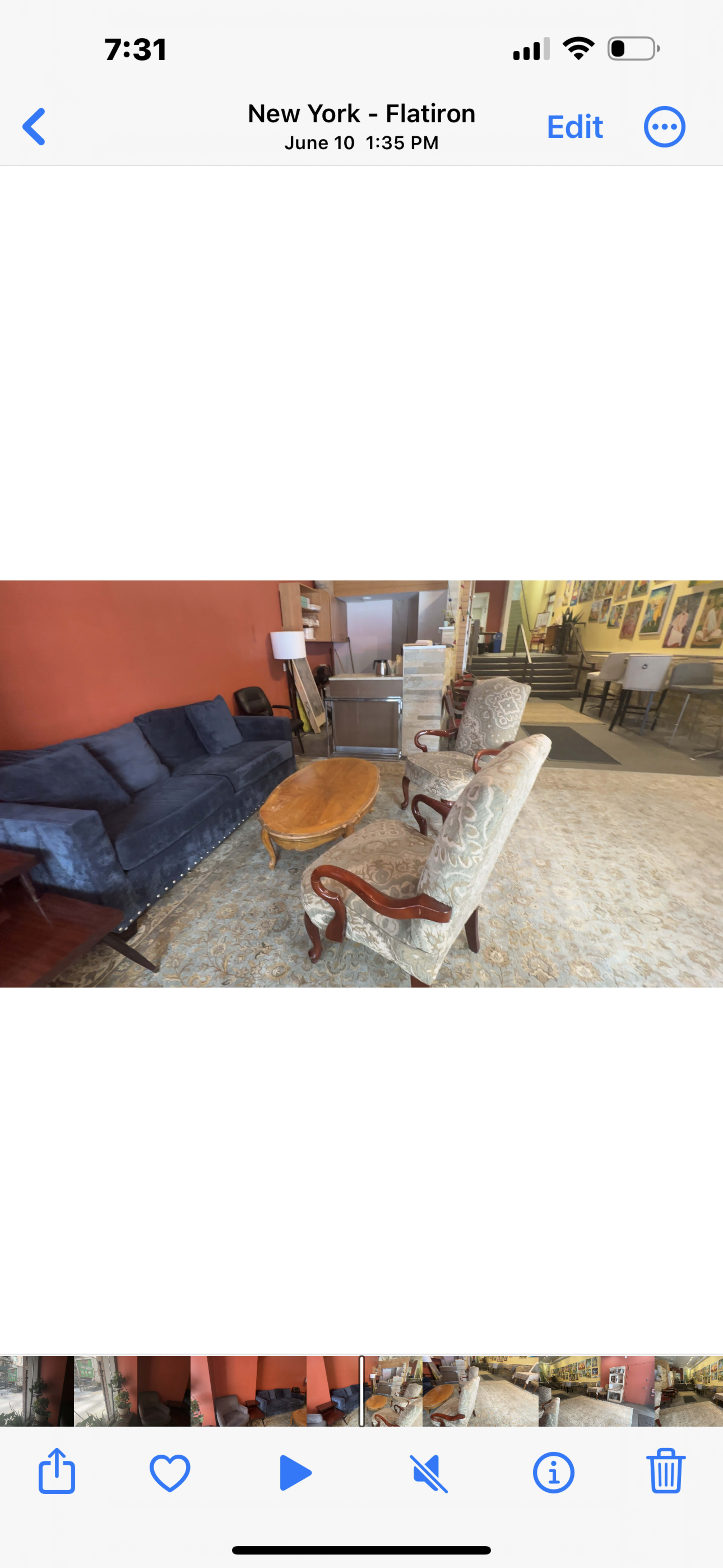A seating area with a blue sofa, two patterned chairs, and a wooden coffee table in a room with red walls.