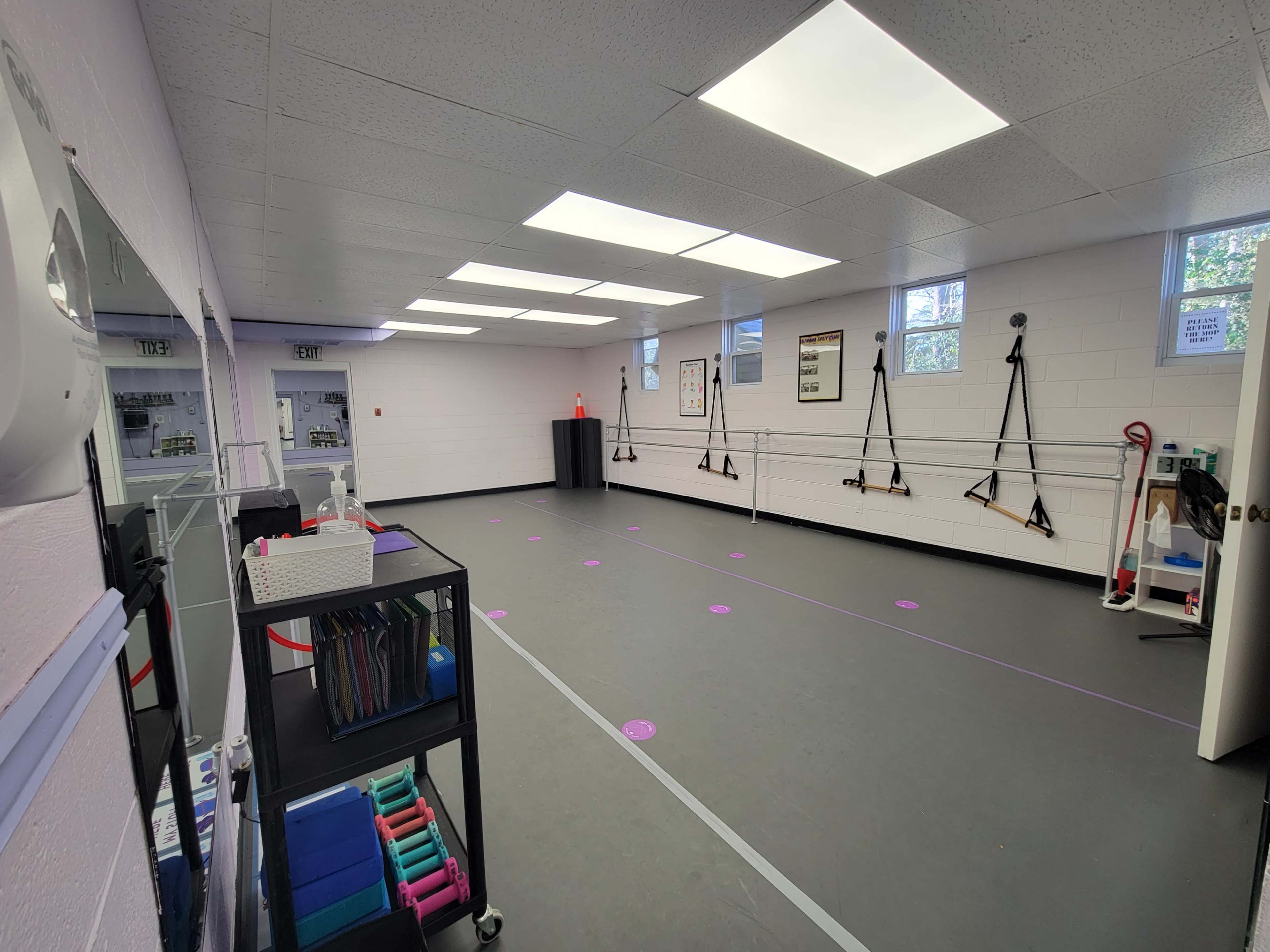 An empty studio space with mirrors, ballet barres, exercise equipment, and wall-mounted cameras.