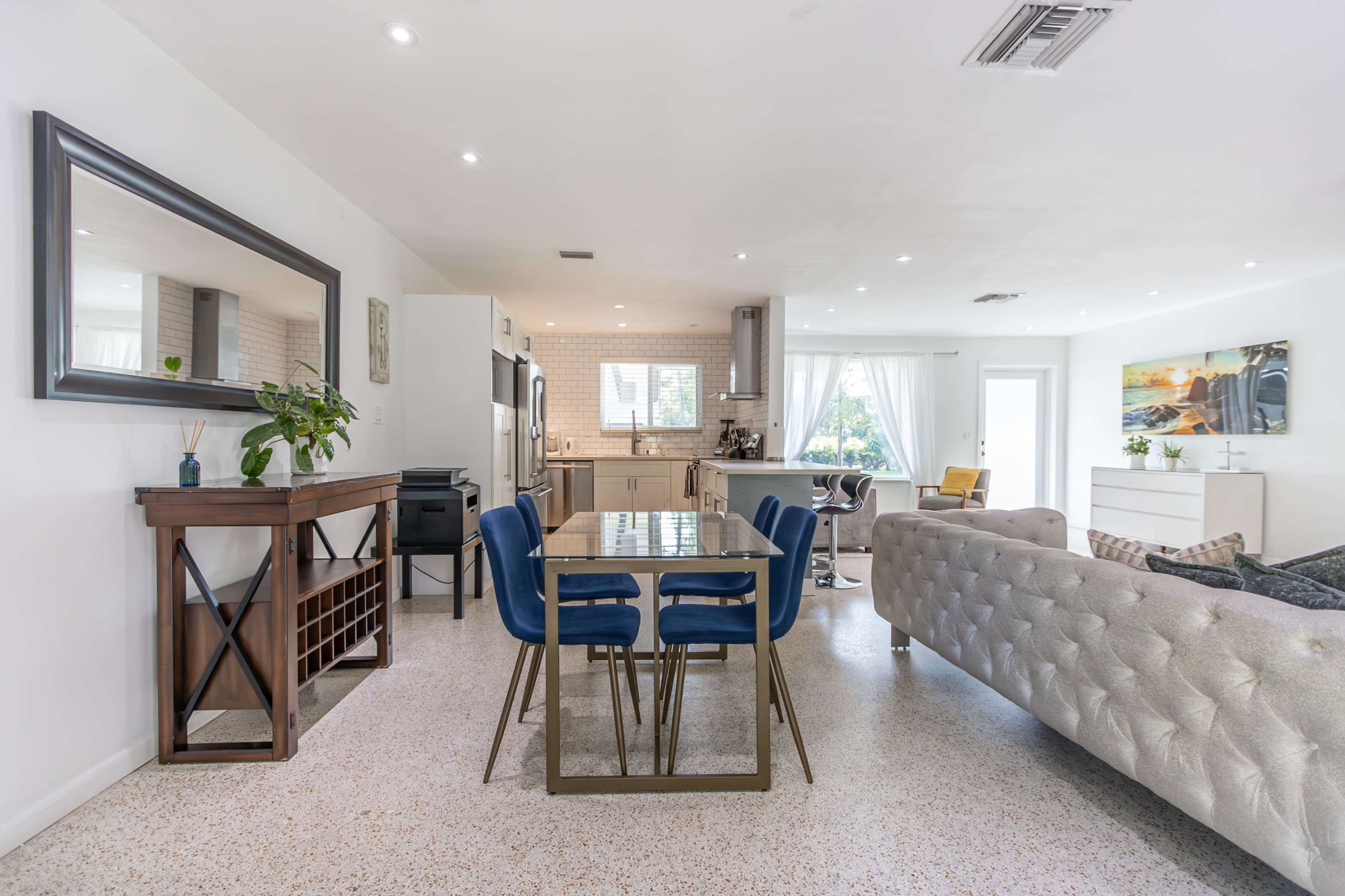 A modern, open-concept living space featuring a dining table with four chairs, a kitchen area, and a cozy living room setup.