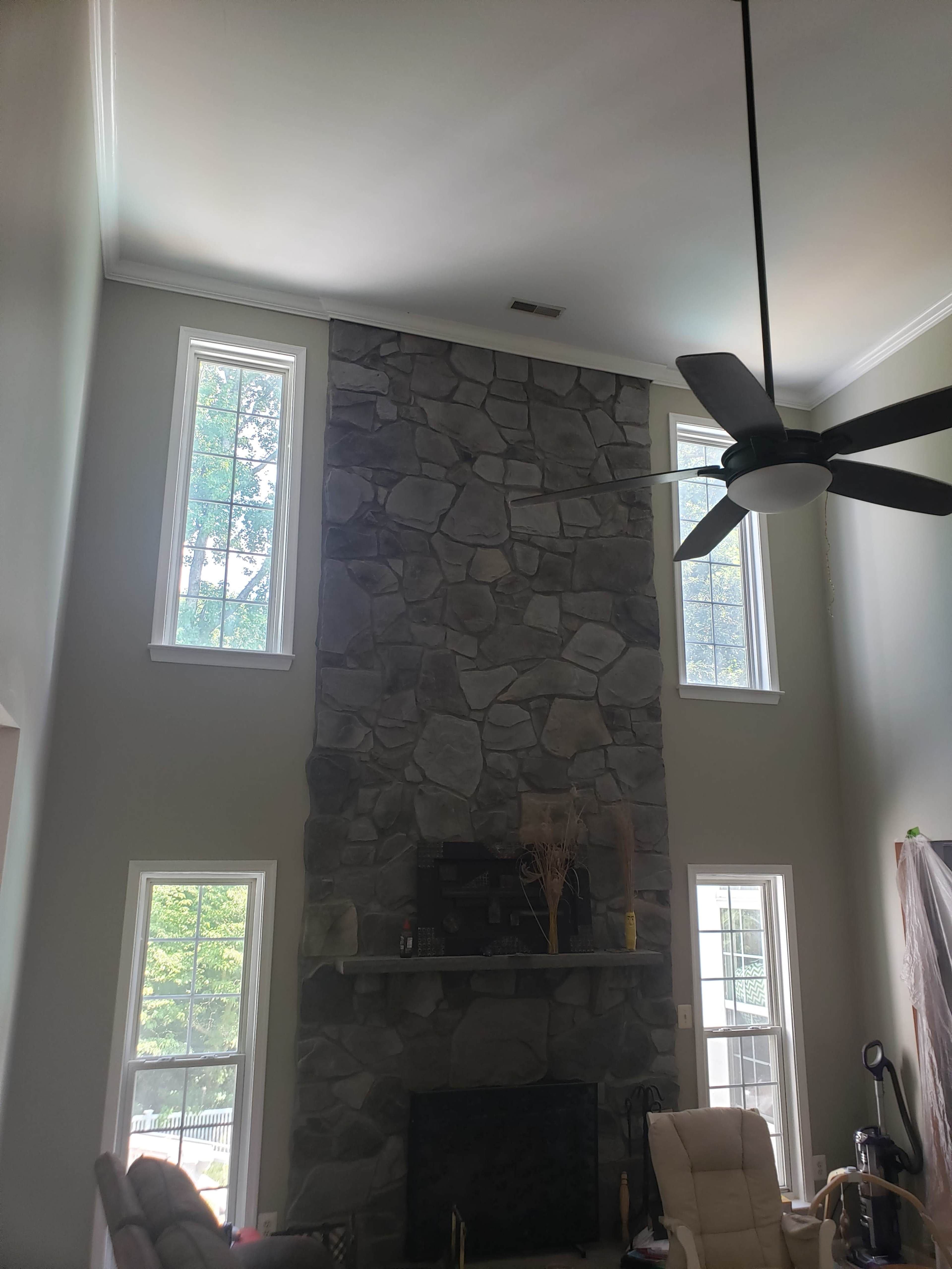 The image shows a spacious living room with a tall stone fireplace and large windows on either side.