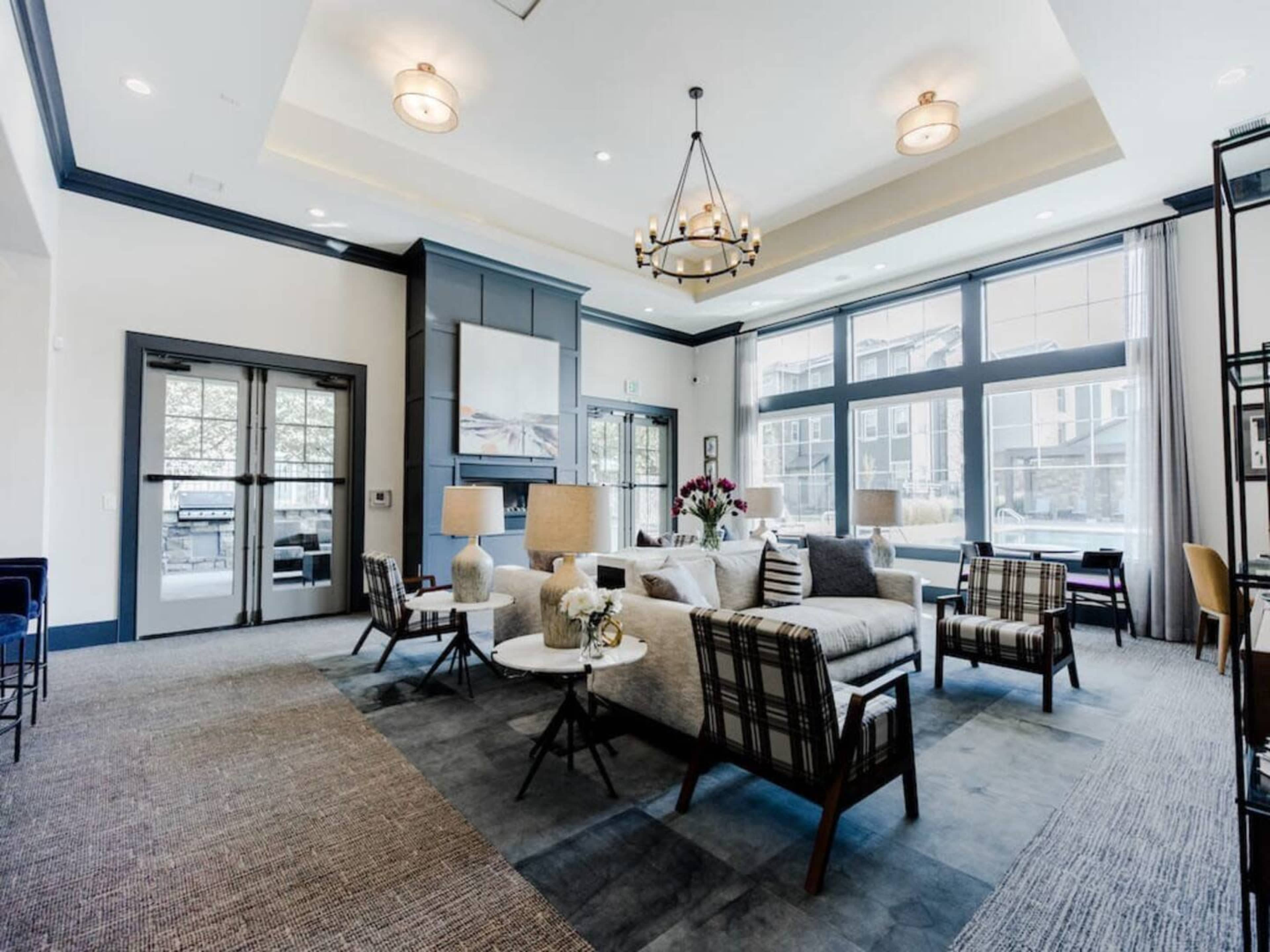 A spacious, elegantly furnished lounge area with large windows, highlighting comfortable seating arrangements and decorative lighting.