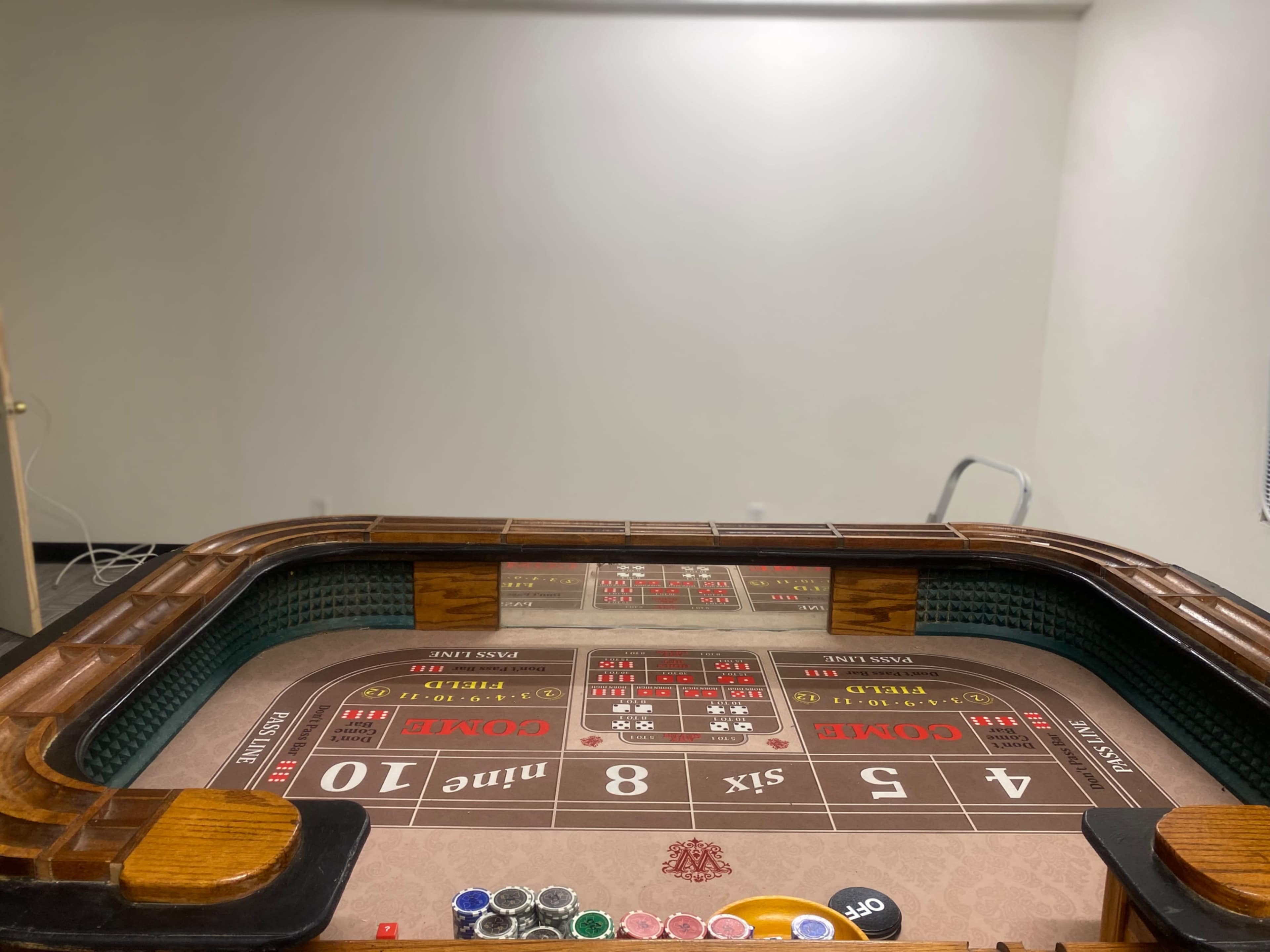 The top view of a roulette table with chips and a clear wall in the background.