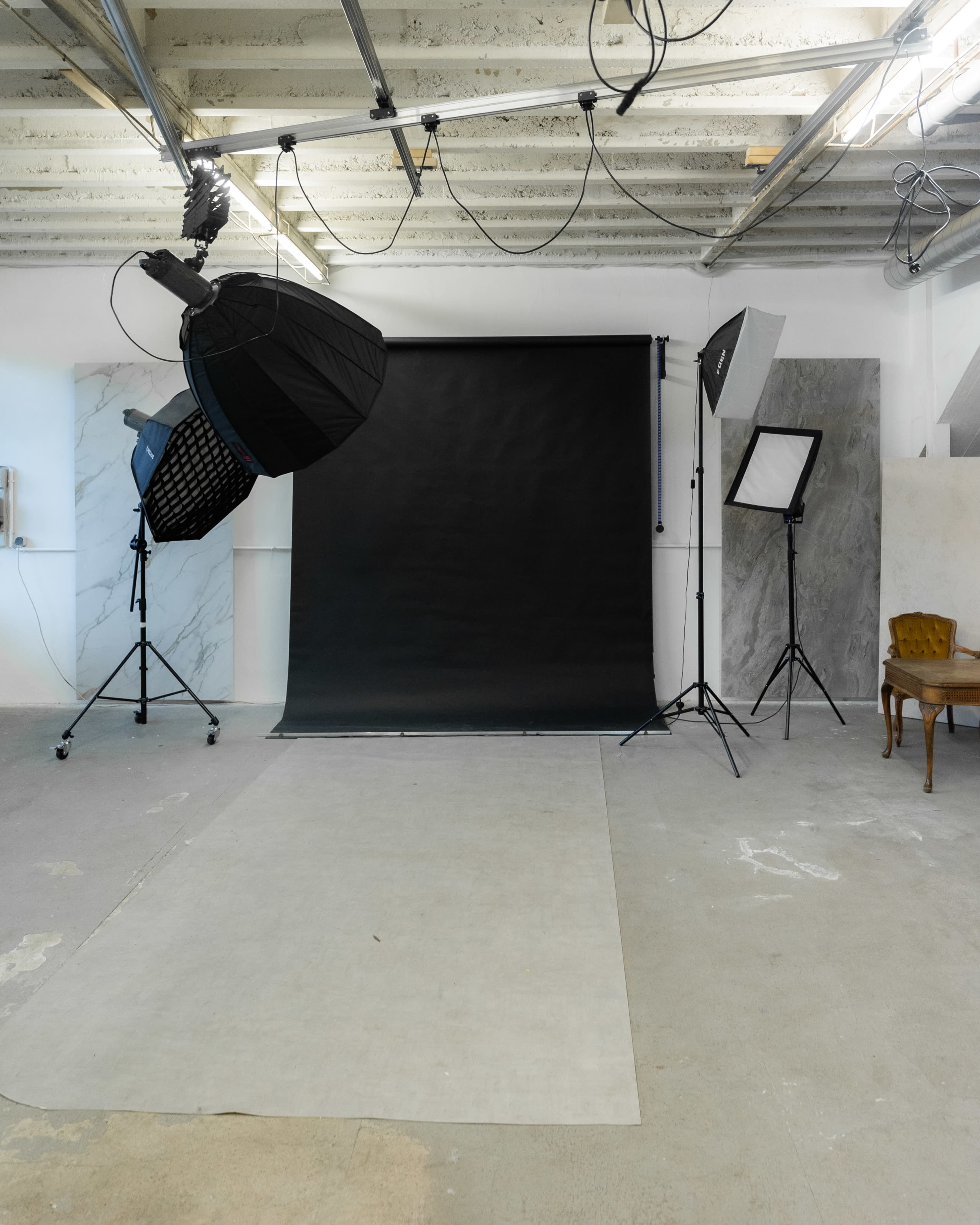 A photography studio with a black backdrop, lighting equipment, and a light-colored carpeted floor.