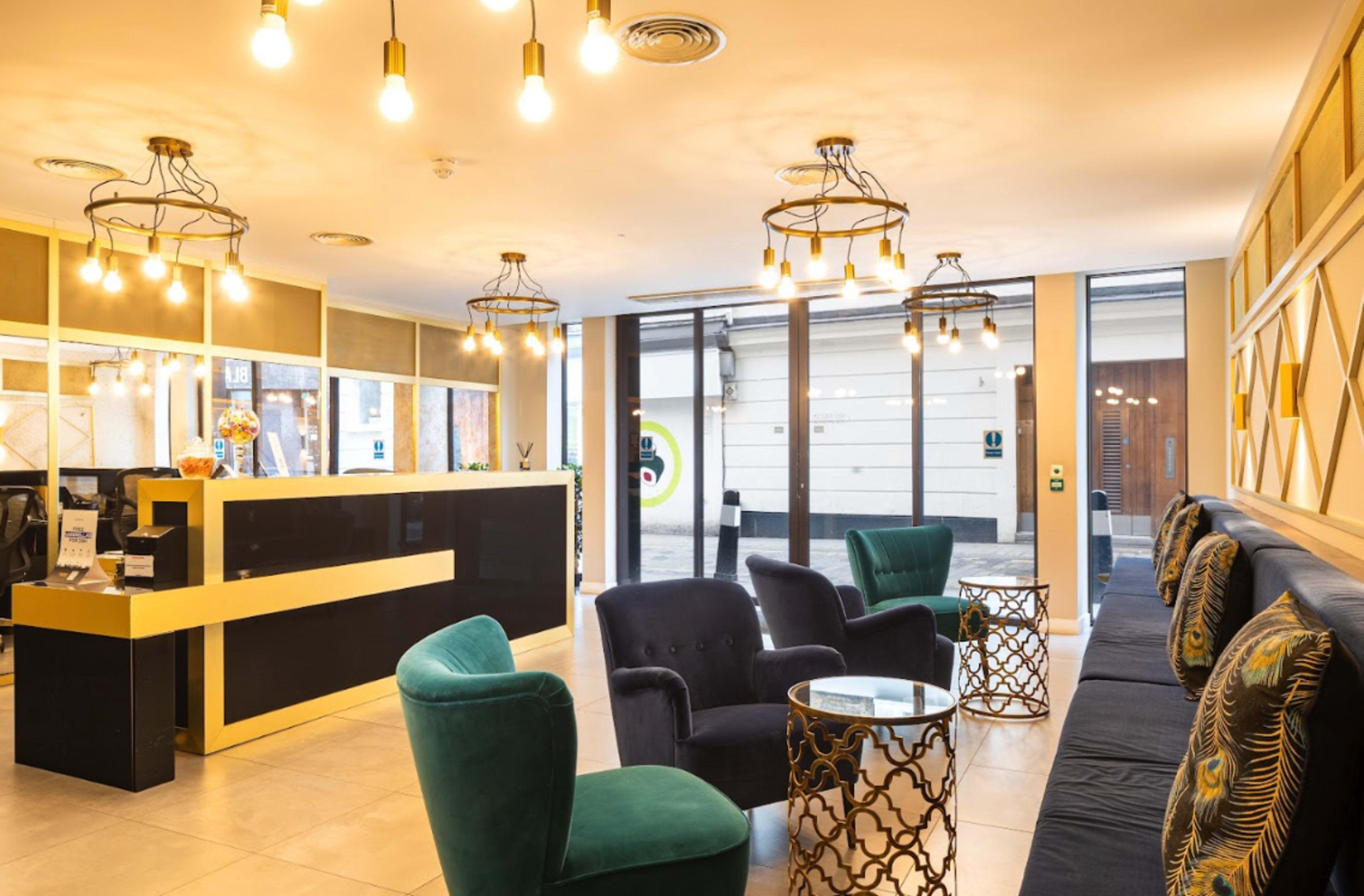 The lobby features a reception desk, dark upholstered seating, and decorative light fixtures.