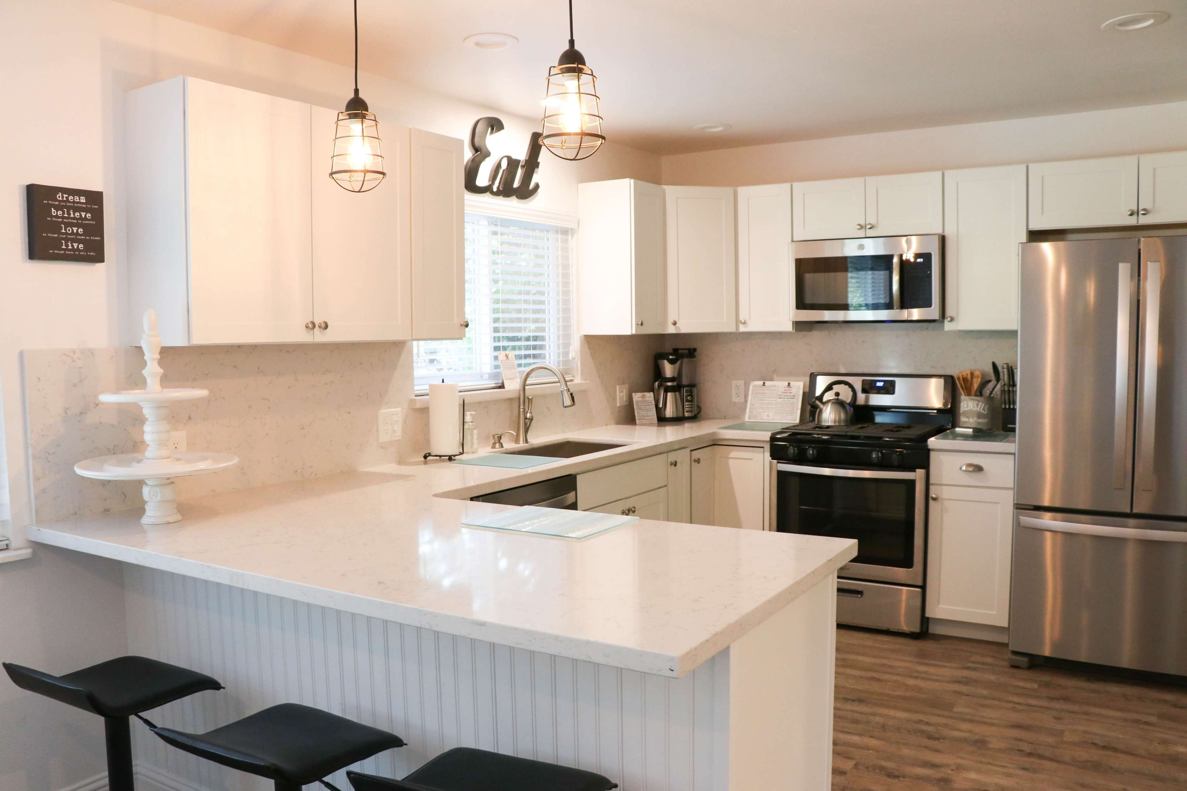 A modern kitchen features white cabinetry, stainless steel appliances, and a spacious island with bar stools.