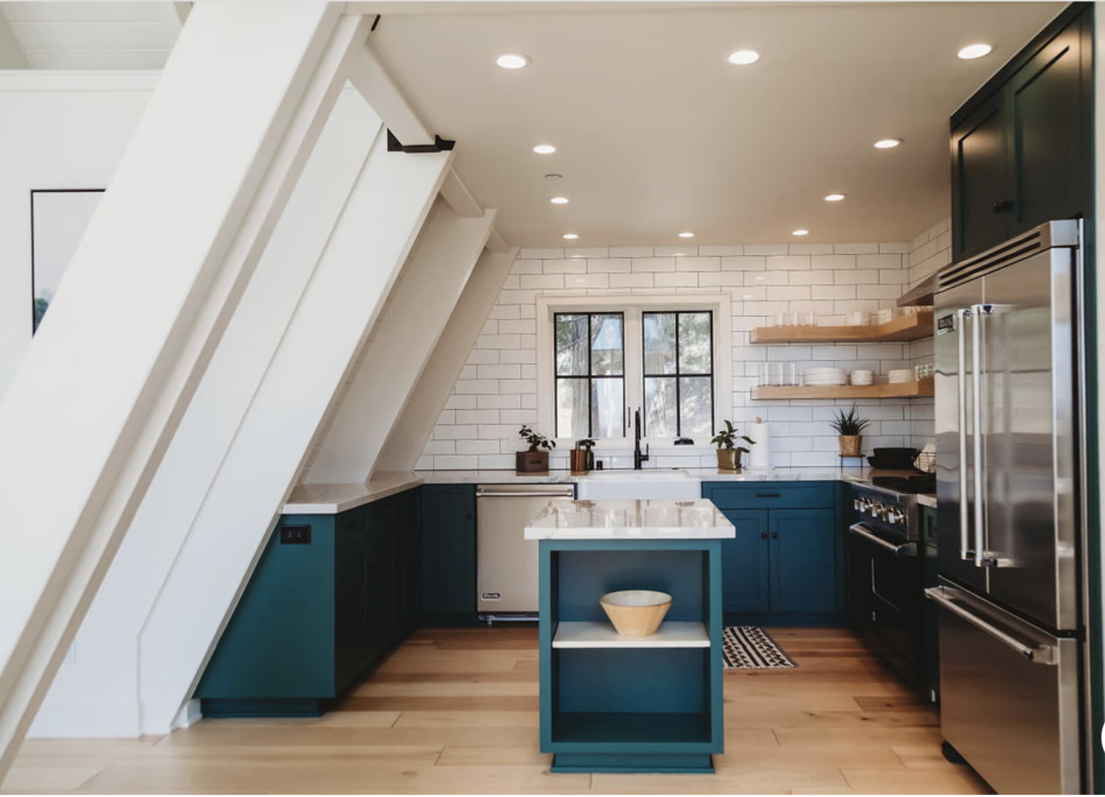 The kitchen features dark blue cabinetry, a white backsplash, and a central island with a white countertop.