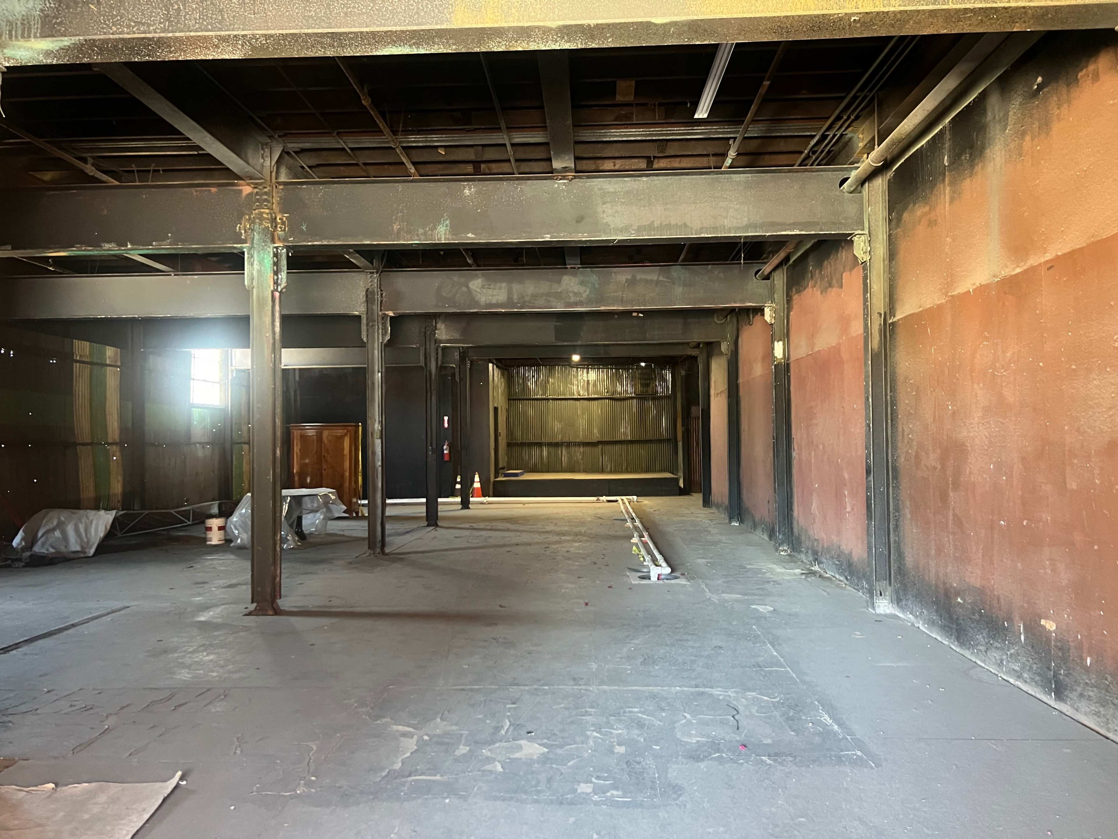 An empty industrial space with exposed metal beams and walls painted in dark colors.