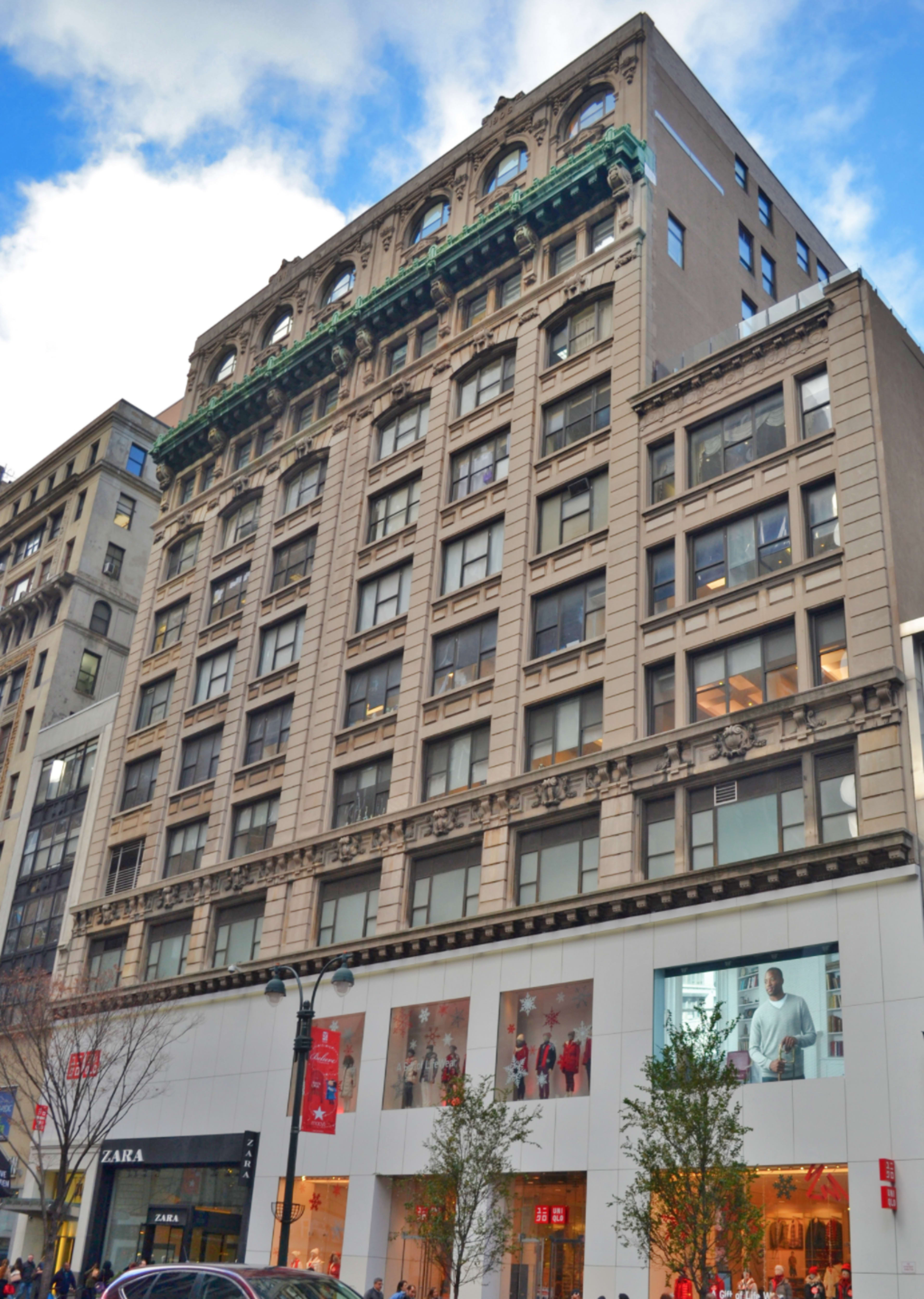 The image shows a multi-story retail building with ornate architectural details, featuring large display windows on the ground floor and a decorative facade on the upper levels.