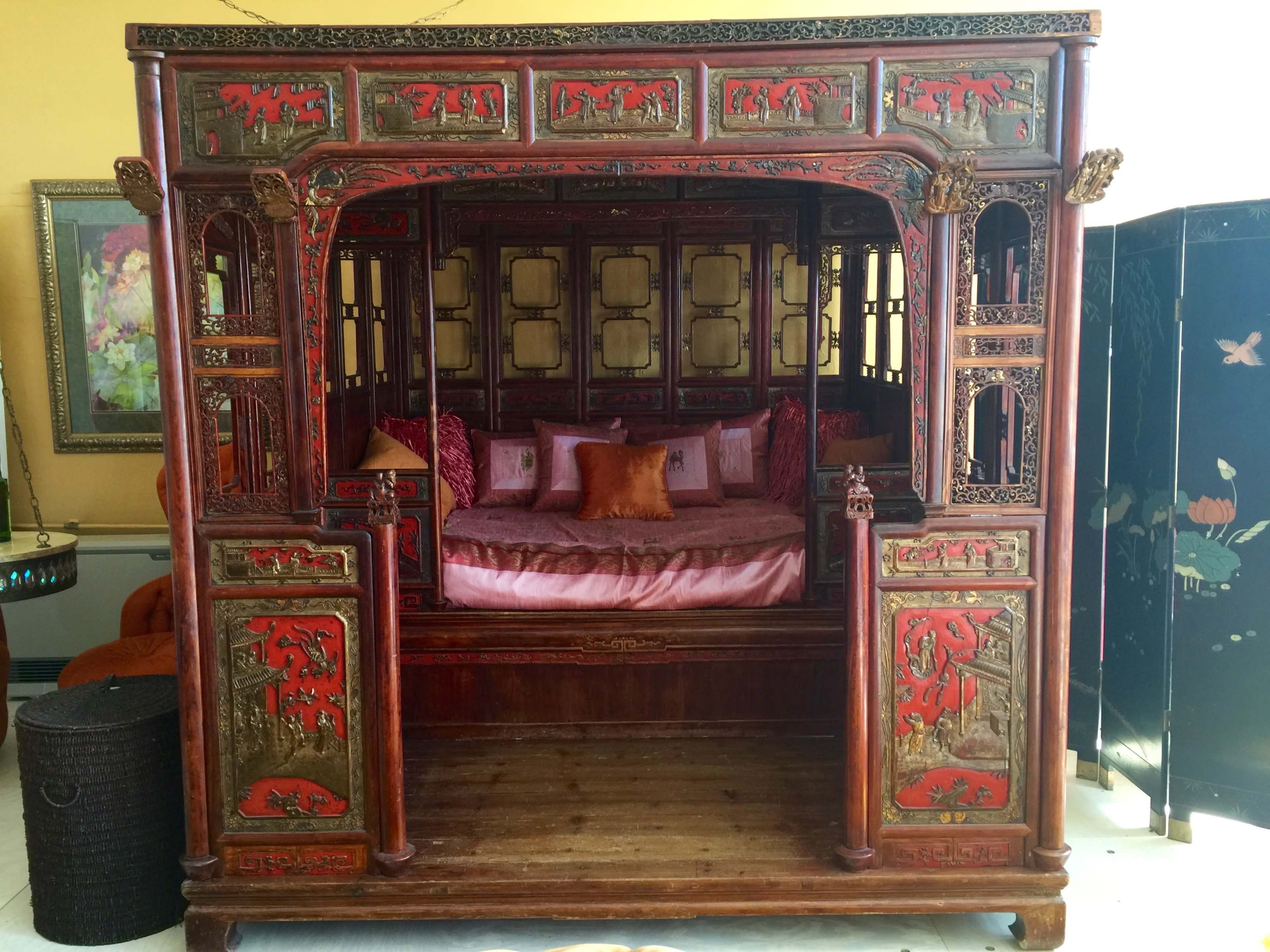 A traditional Chinese wood-framed couch with intricate carvings and decorative elements, featuring a circular cushioned area and plush seating.