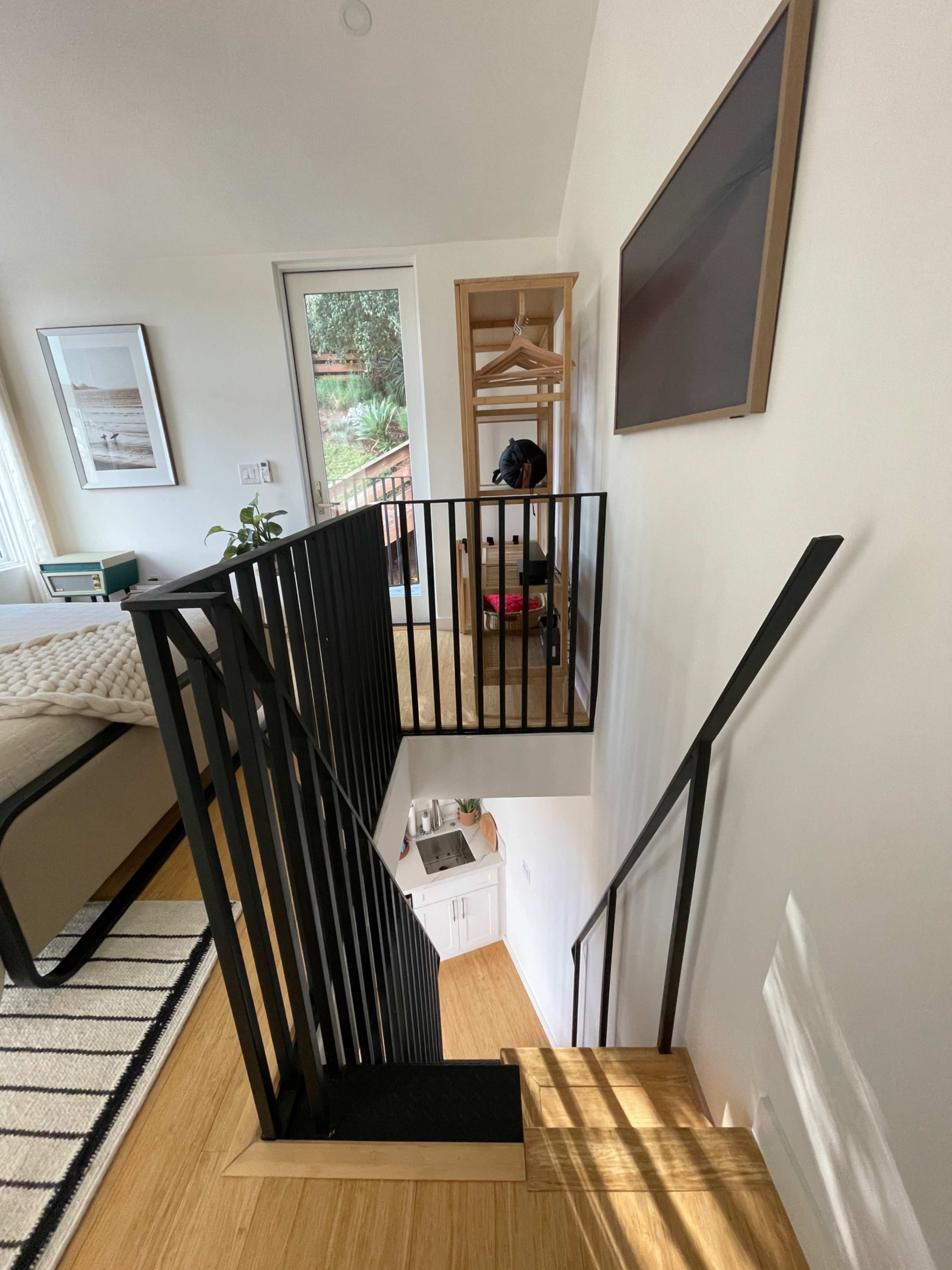 The image shows a modern staircase with black railing, leading to an upper level in a well-lit interior space.