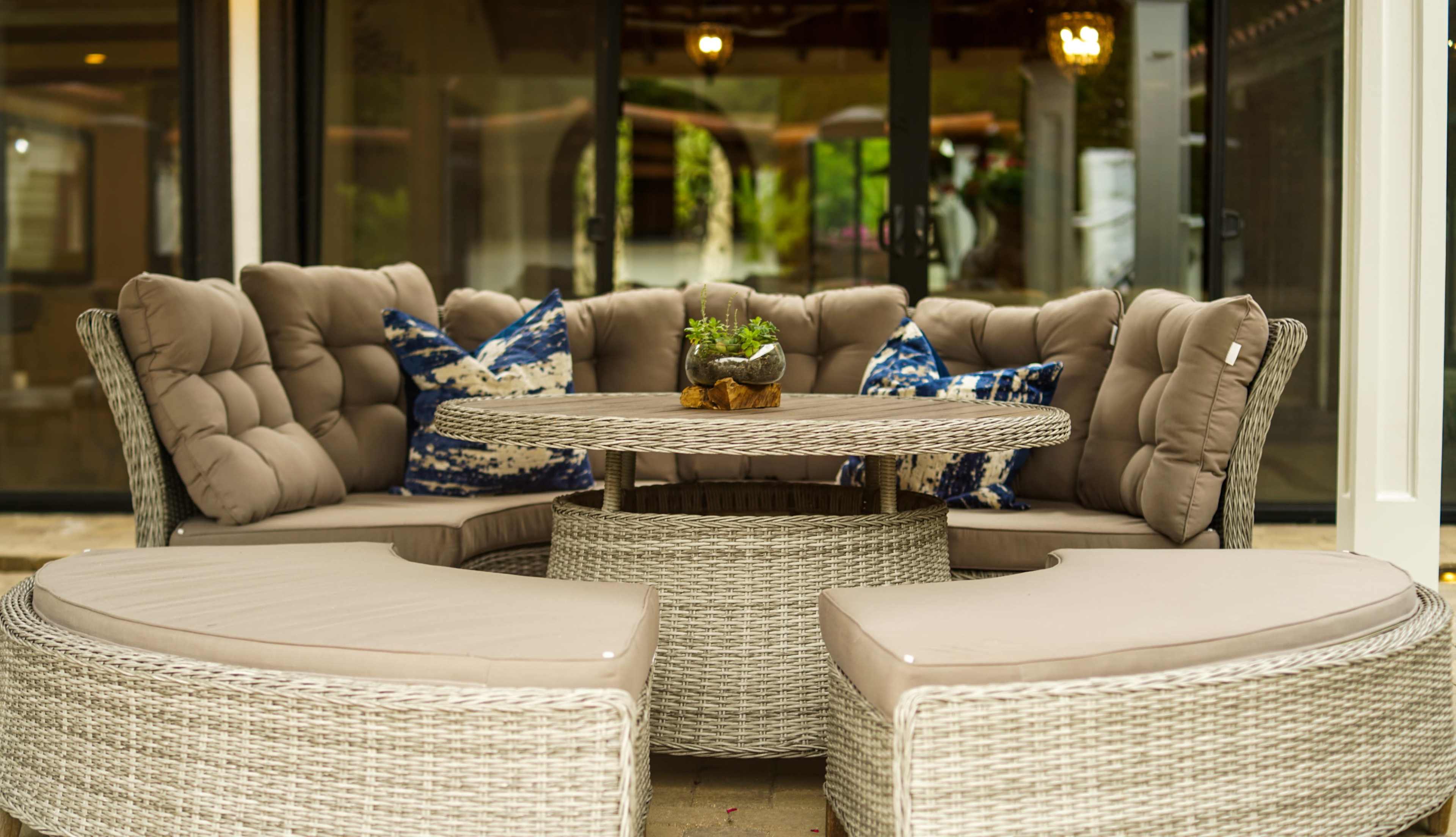 A round outdoor seating arrangement with plush cushions and a matching table surrounded by curved couches.