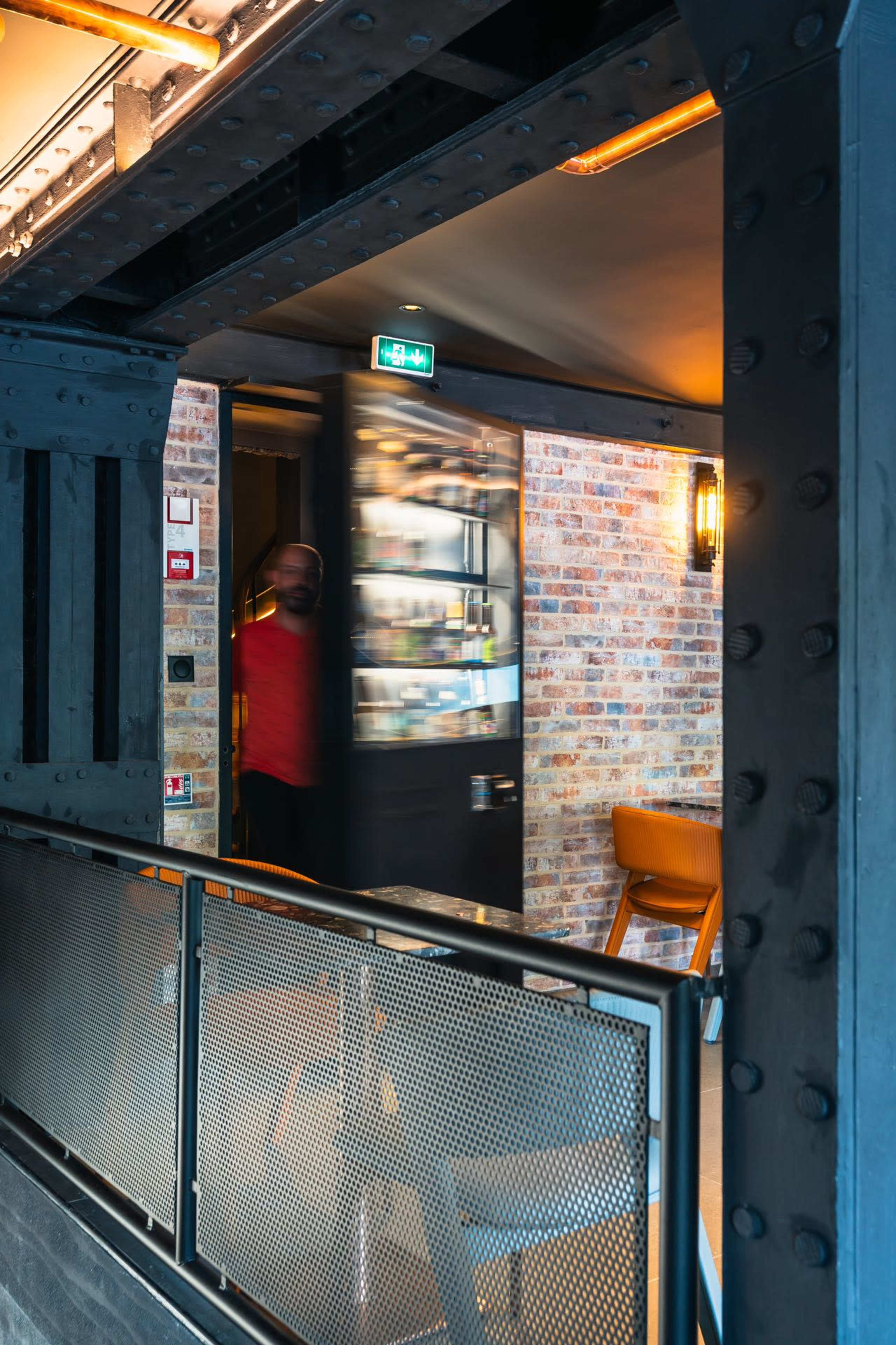 A person exits through a partially opened door in a modern, industrial-style interior.