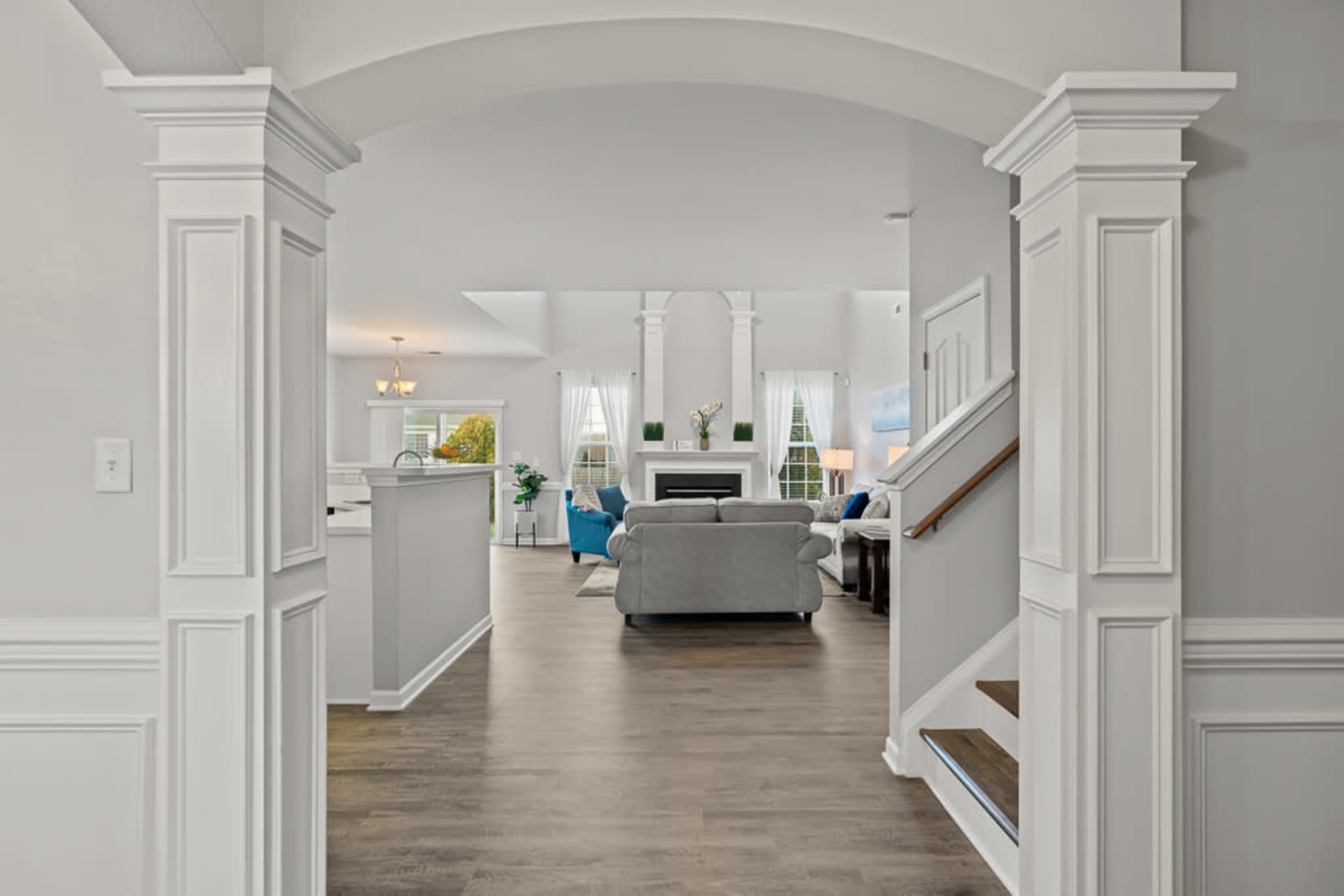 A spacious, welcoming entryway leading into a bright living area with a sofa, a fireplace, and large windows.