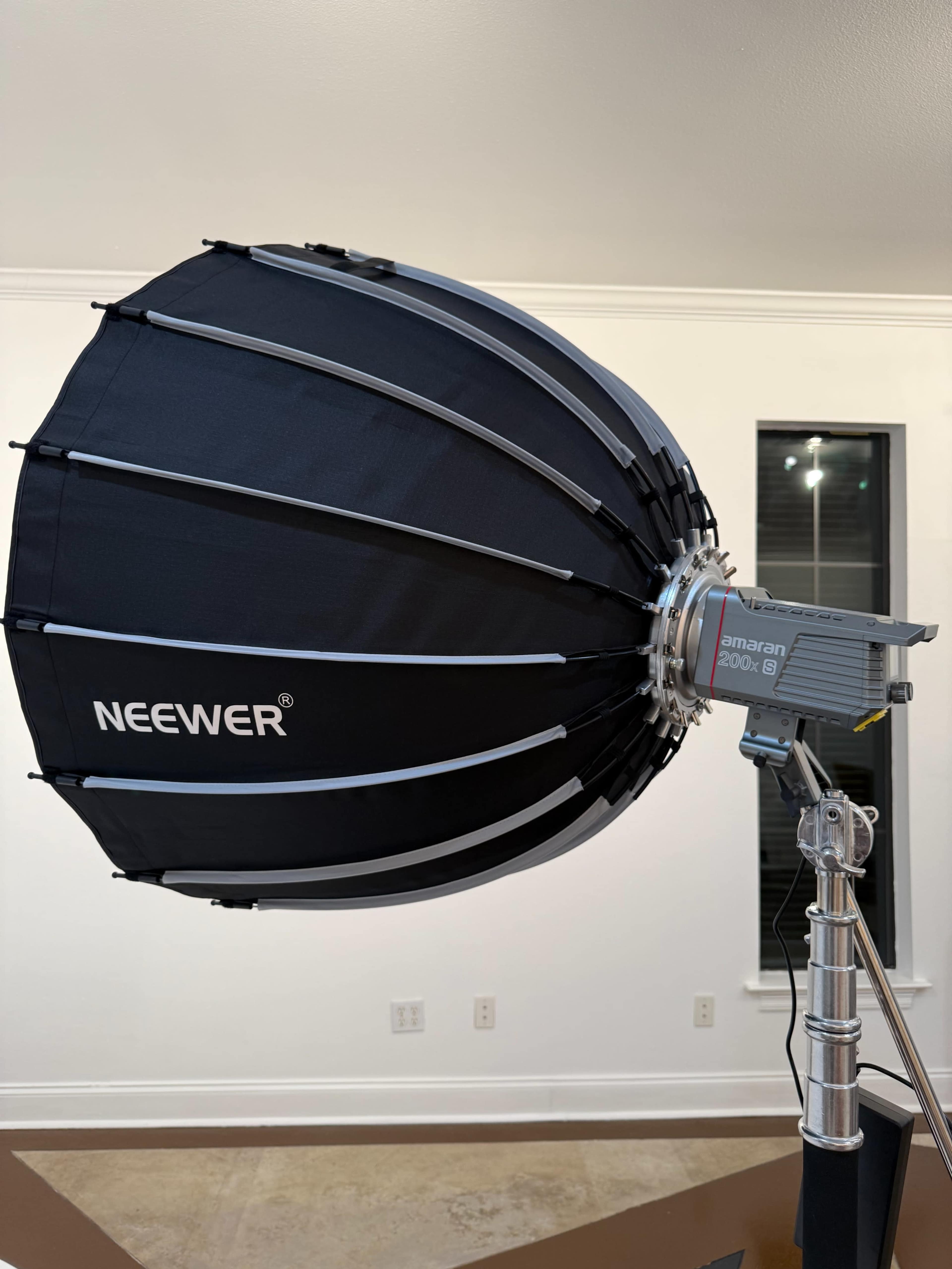 A large collapsible softbox with a spotlight attached is set up on a light stand.