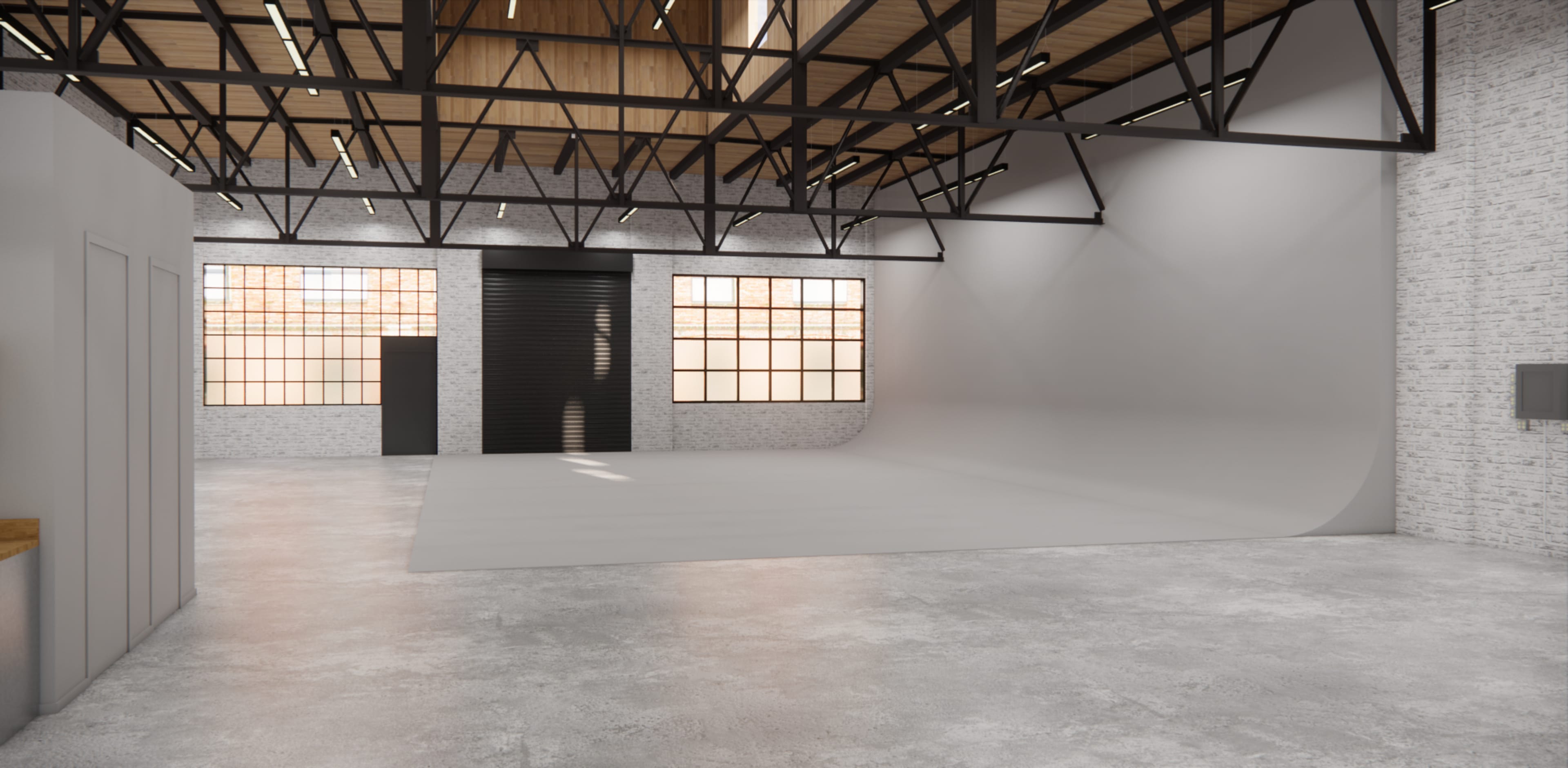 An empty industrial-style studio space with large windows, a concrete floor, and a curved backdrop wall.