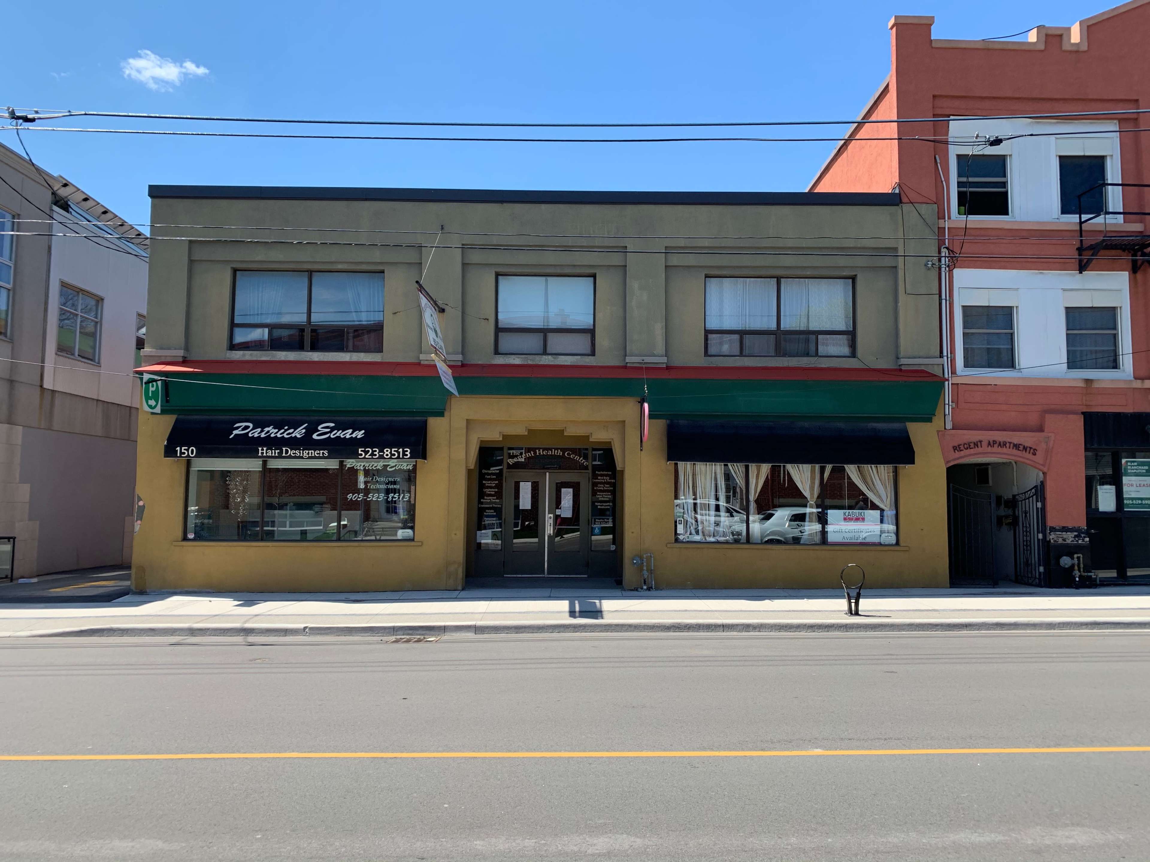 A two-story commercial building with a green facade and a sign for "Patrick Eats Hair Designers" on the left.