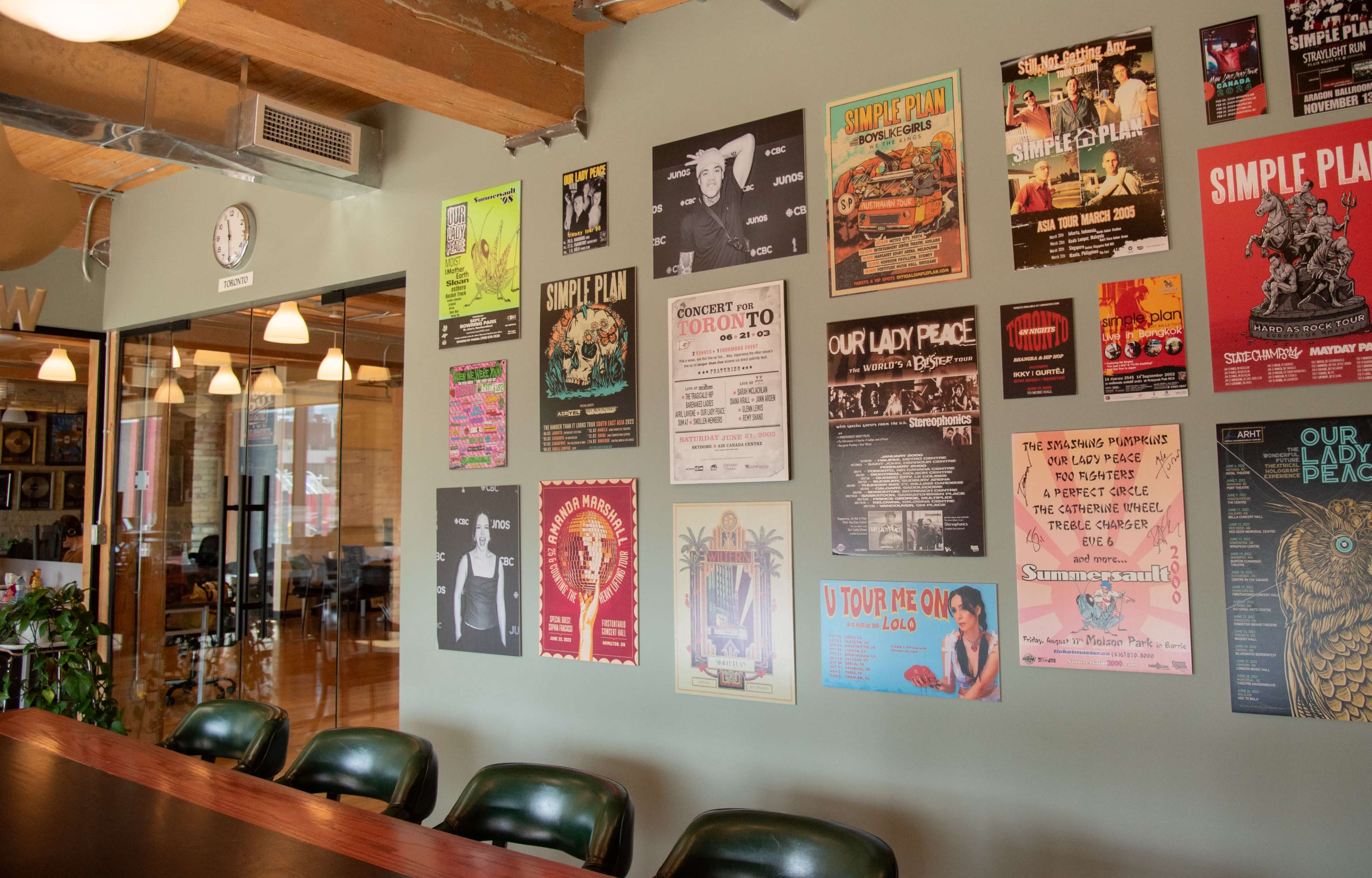 The image shows a modern office space with a long table and a wall covered in various colorful posters and flyers.